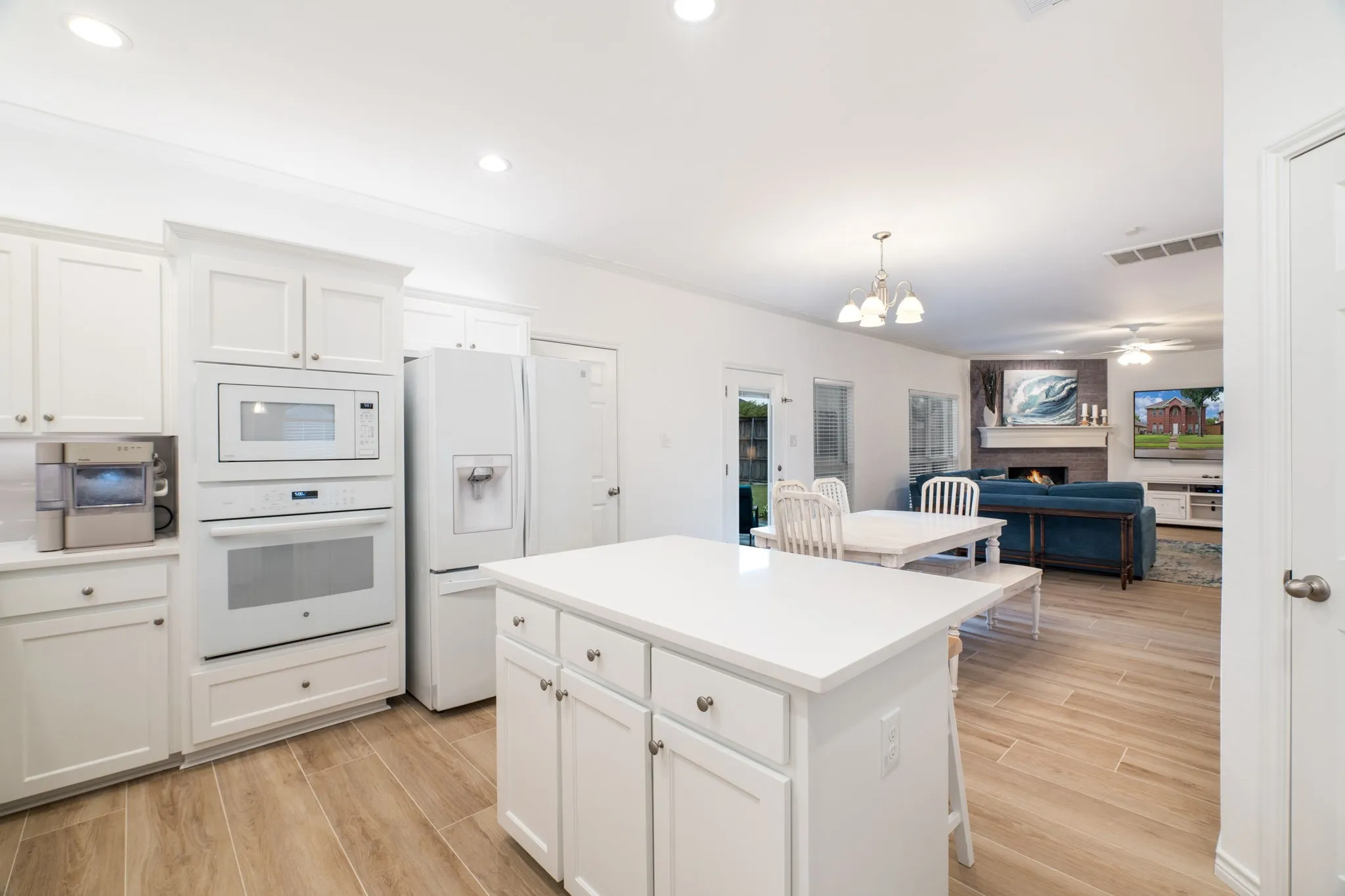 White cabinetry, built-in oven and microwave, and wood-finish flooring