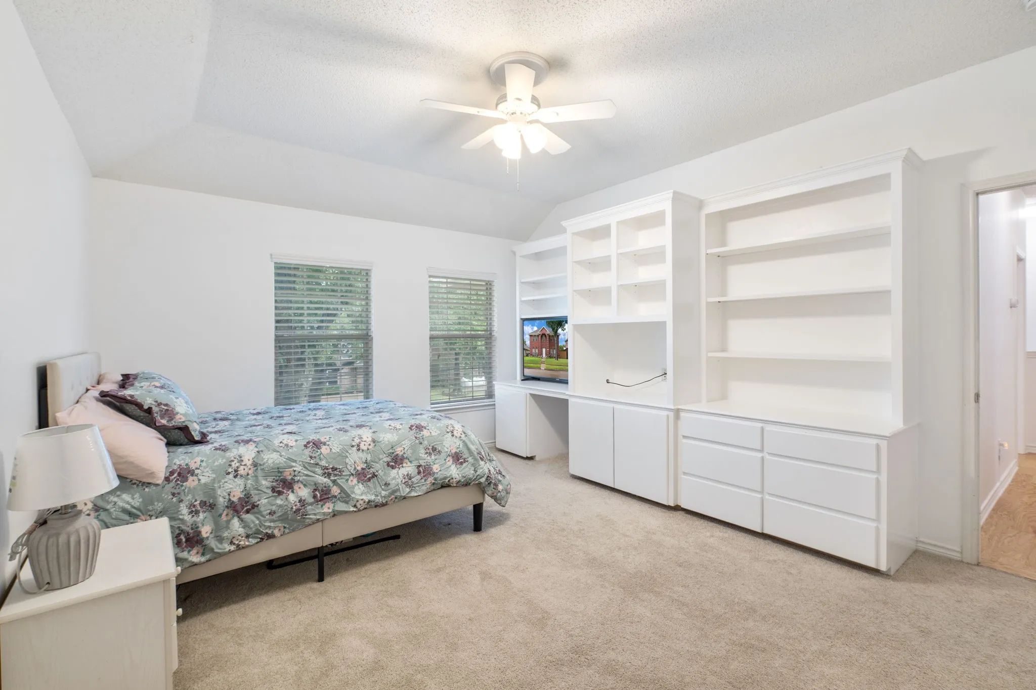 Bedroom 2 Built-in custom cabinetry with shelving and drawers, textured ceiling, two windows with blinds, and a ceiling fan with light fixture