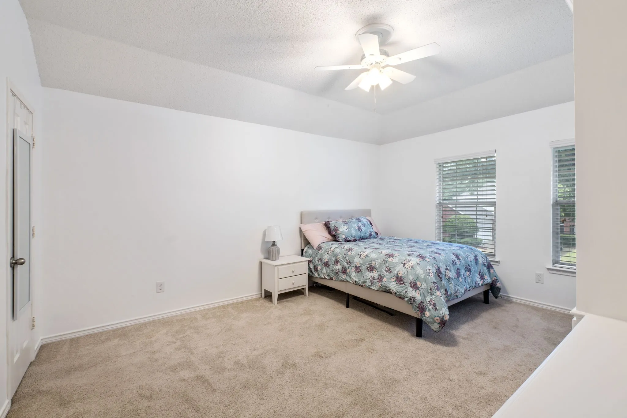Bedroom 2 Built-in custom cabinetry with shelving and drawers, textured ceiling, two windows with blinds, and a ceiling fan with light fixture