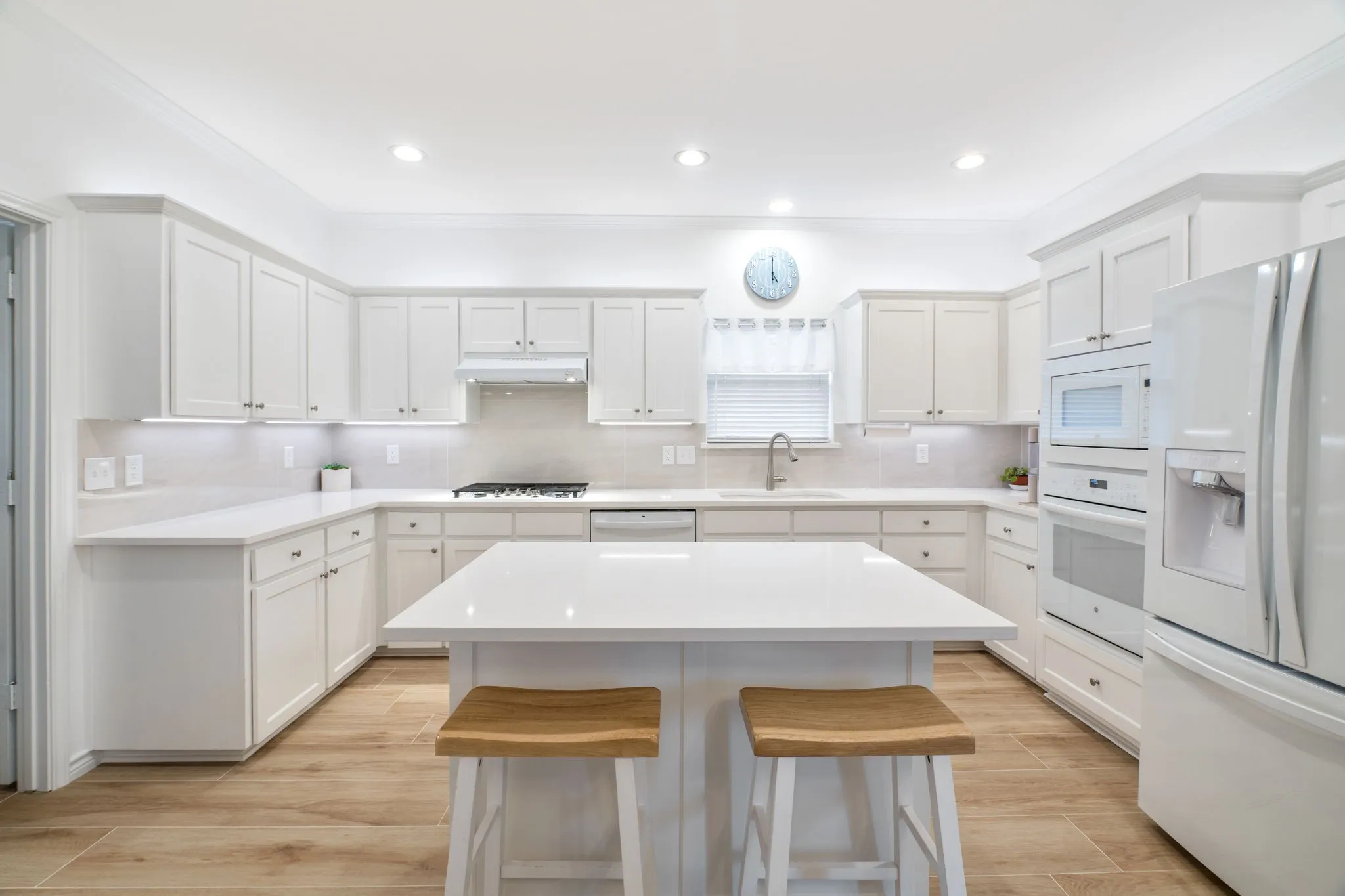 Modern kitchen featuring white cabinetry, a central island with a solid surface countertop, stainless steel appliances, and wood-finish flooring