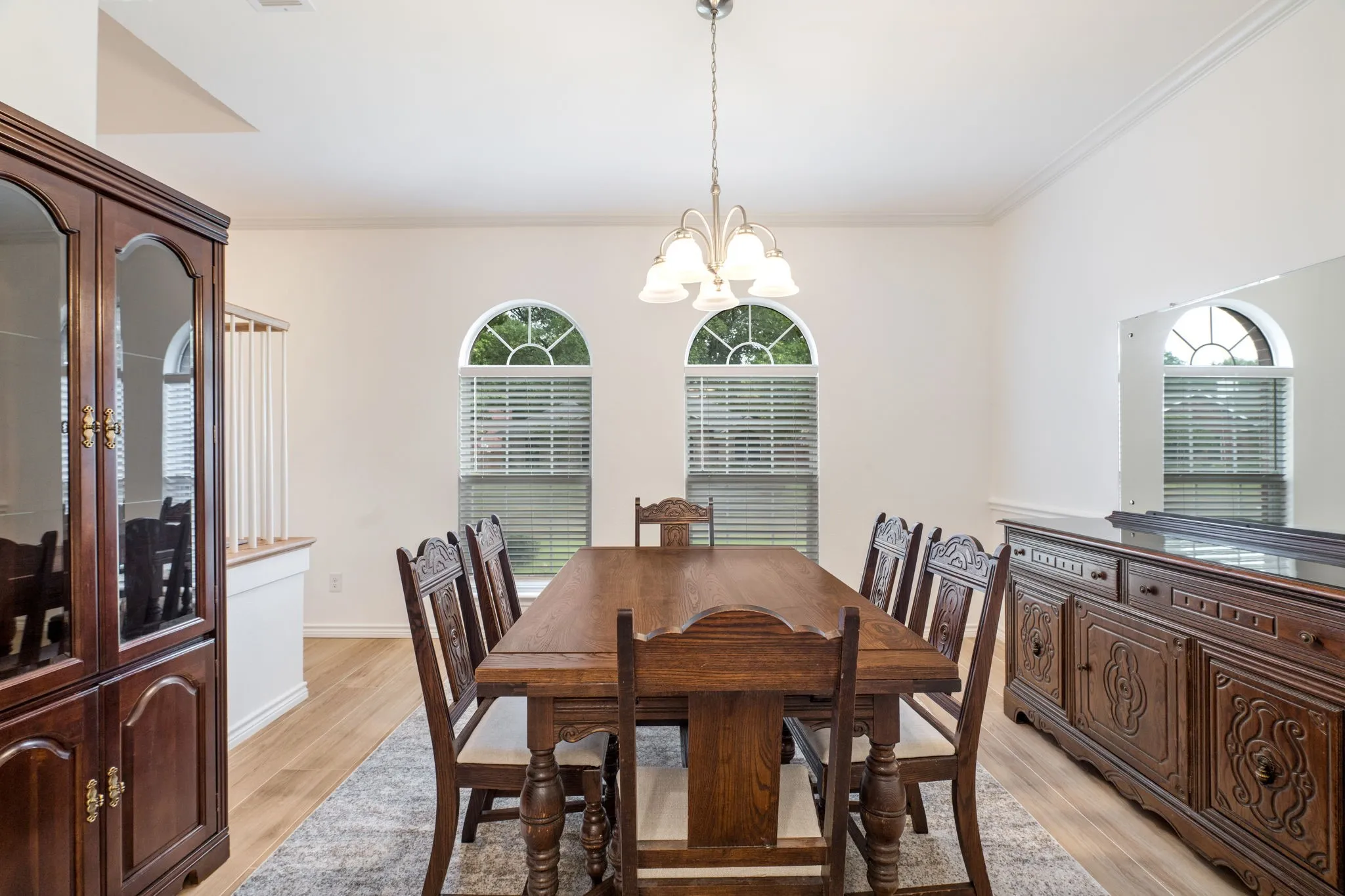 Vaulted ceiling, two arched windows with blinds, wood-finish flooring, and a chandelier lighting fixture