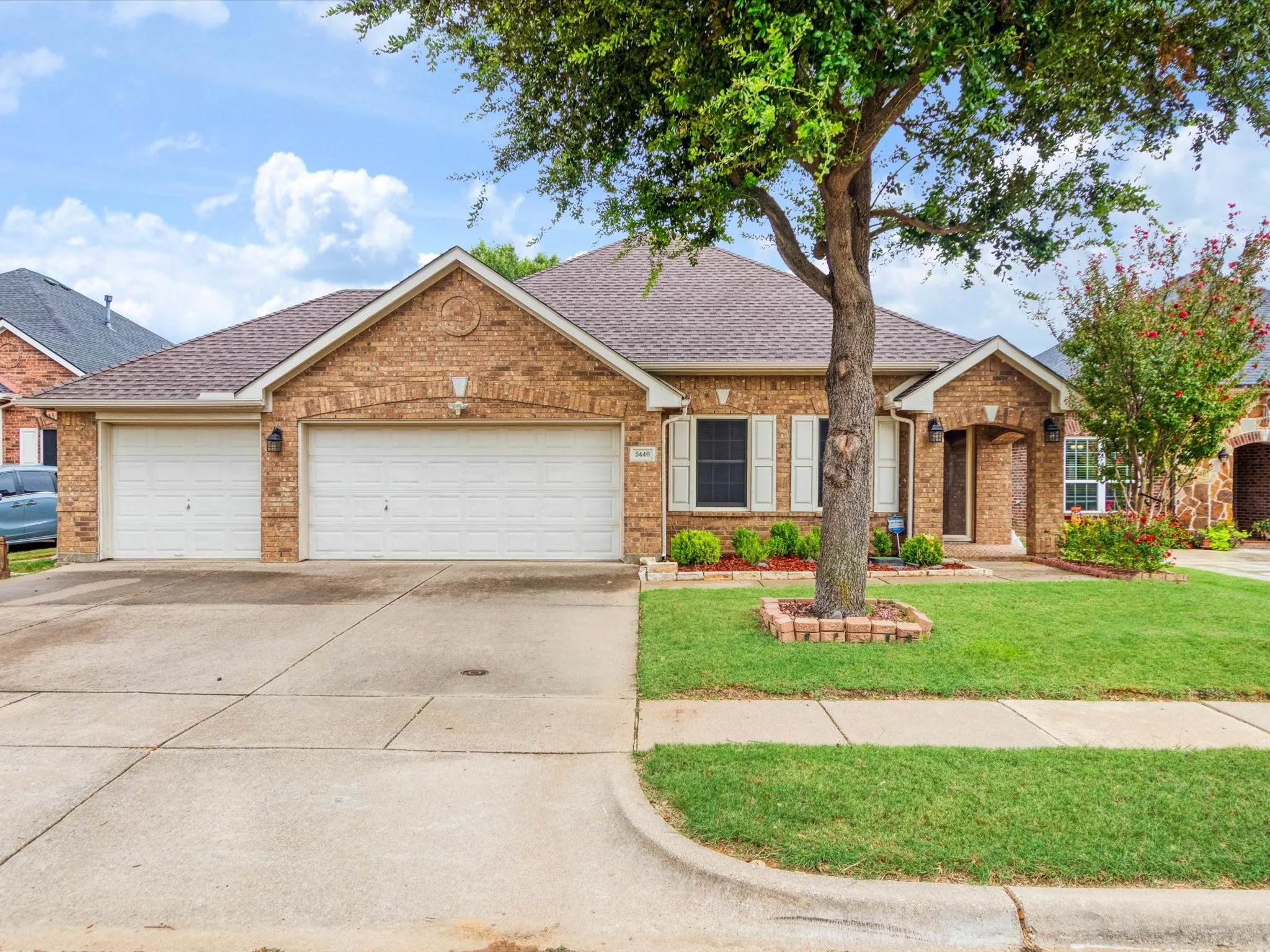 Brick exterior with a shingled roof, two-car garage, and a concrete driveway