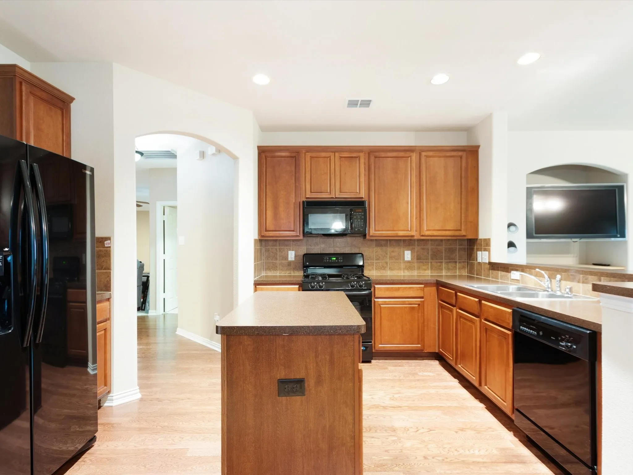 Kitchen featuring wood-finish flooring, recessed lighting, wood cabinetry, and a central island