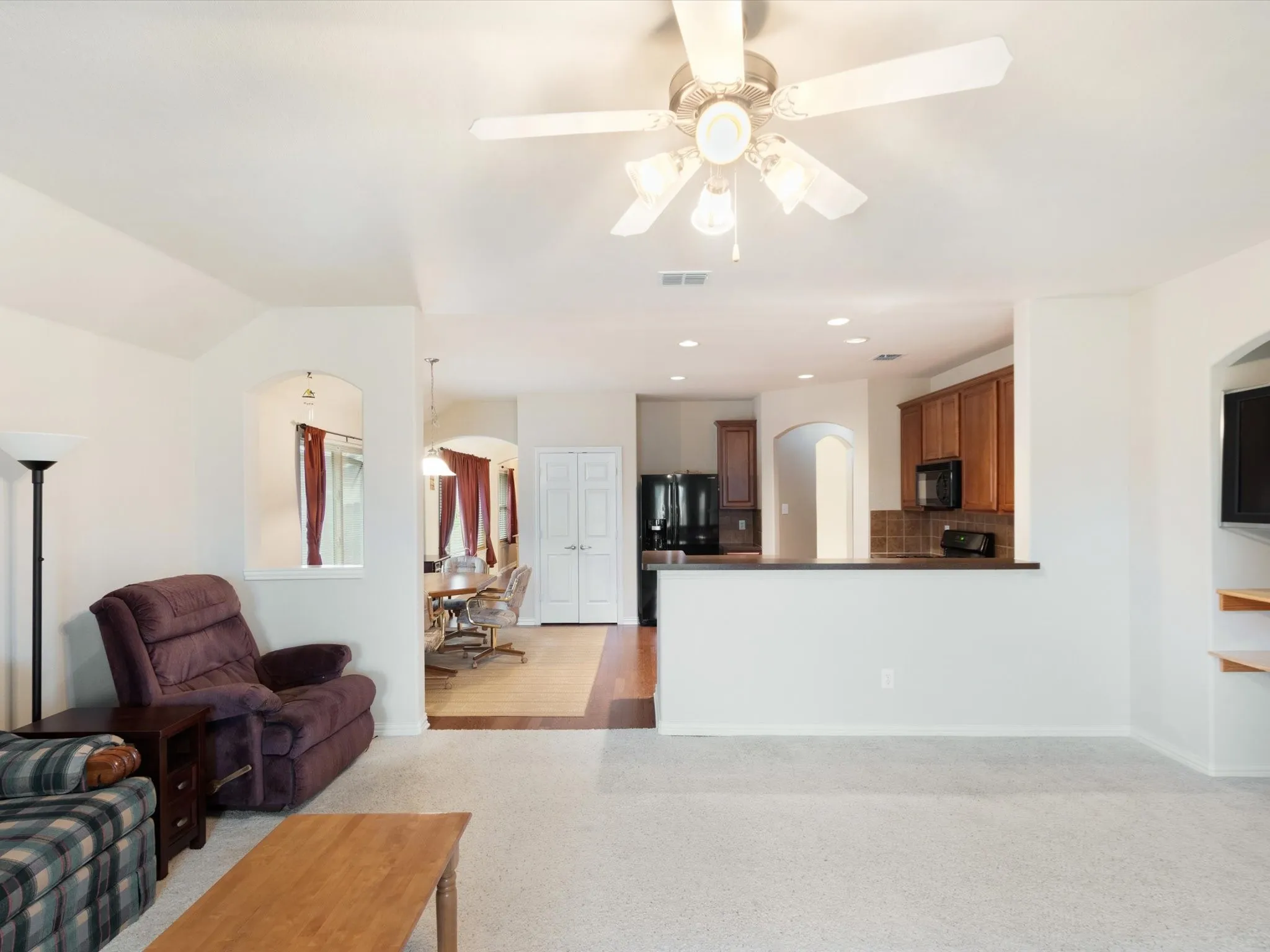 Recessed lighting, arched entryways, wood-finish flooring, built-in shelving, and a ceiling fan with light fixture