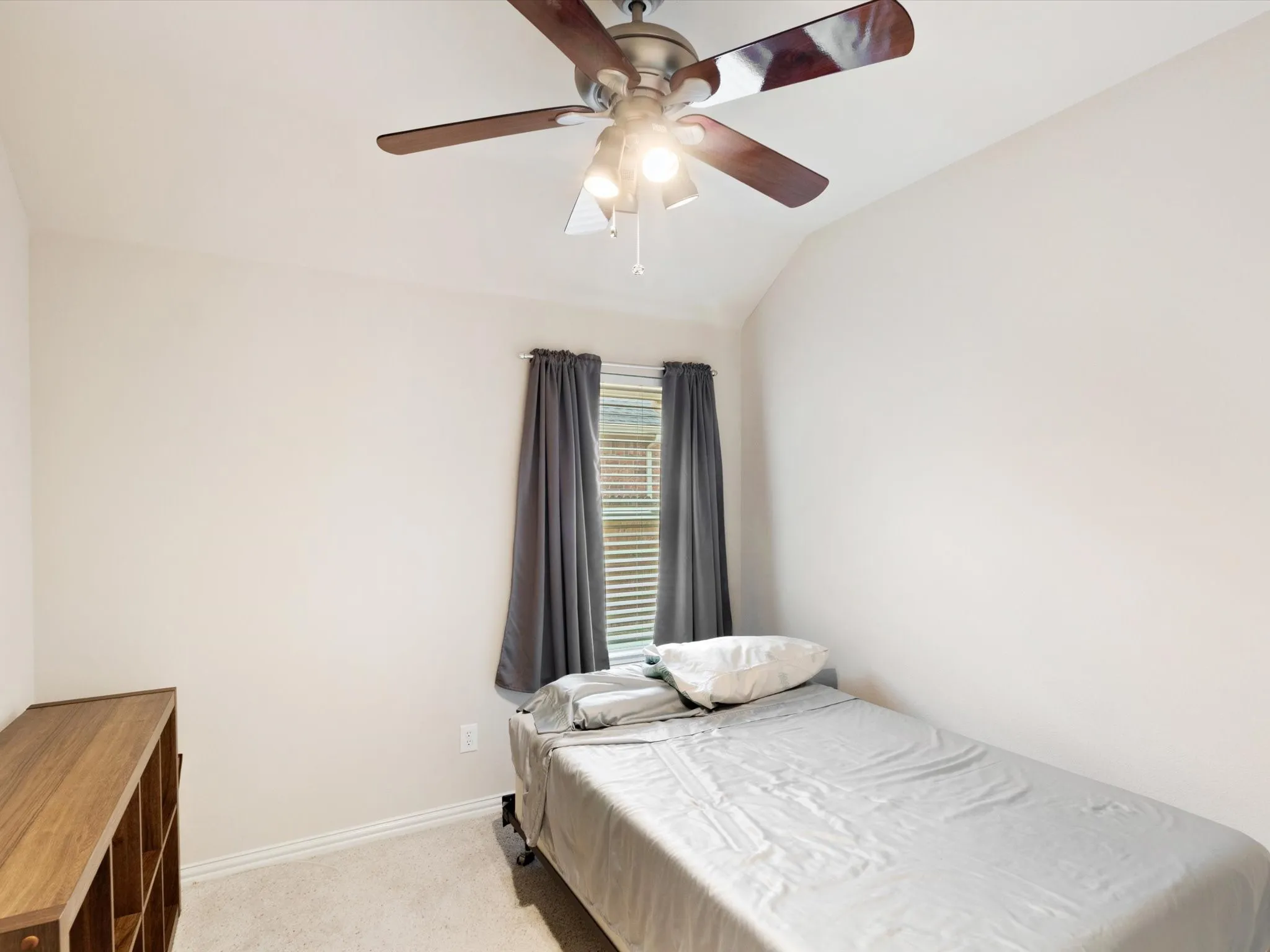 Vaulted ceiling with an attached ceiling fan, window with blinds, and light-colored wall-to-wall carpeting