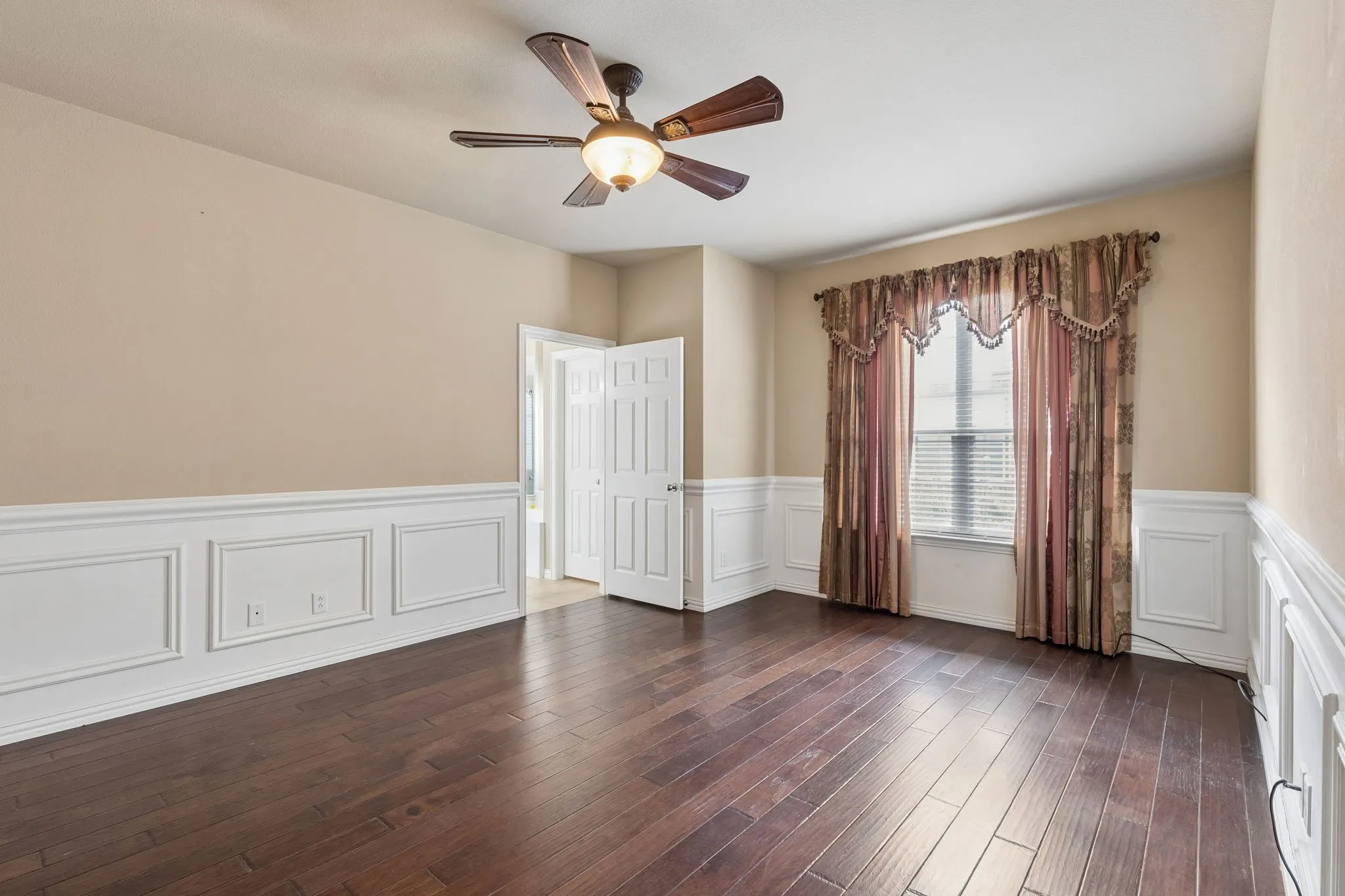 Hardwood flooring, decorative wall paneling, ceiling fan, room for seating area