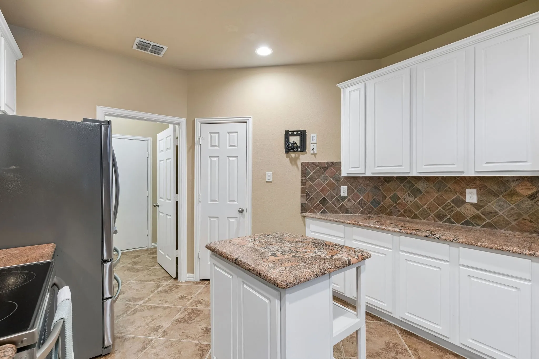 White cabinetry, central island, tile flooring, spacious pantry