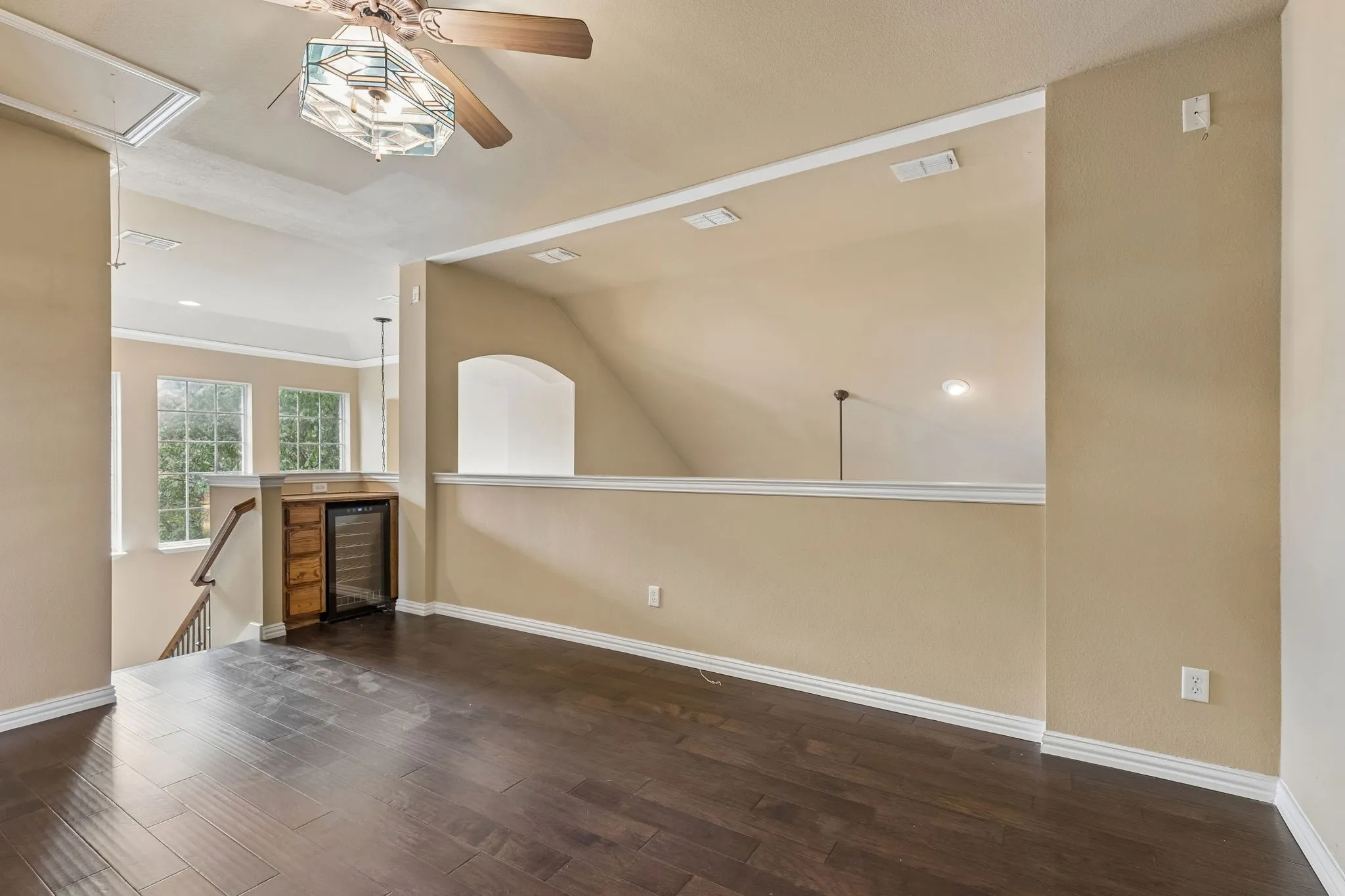 Wood-finish flooring, built-in wood cabinetry, ceiling fan with light fixture, and open to Living Room below