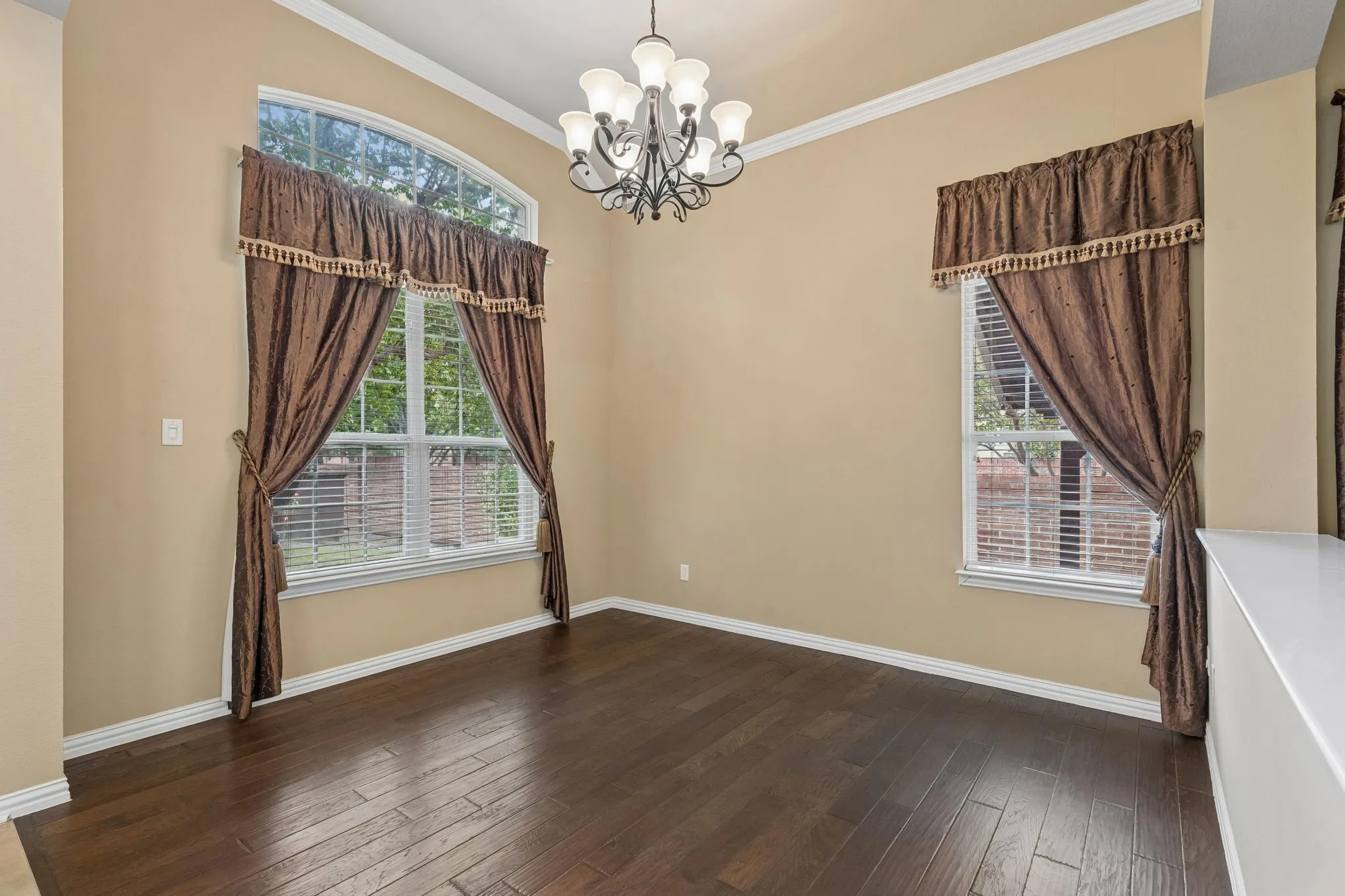 High ceilings featuring crown molding, arched transom window, wood-finish flooring, and a chandelier