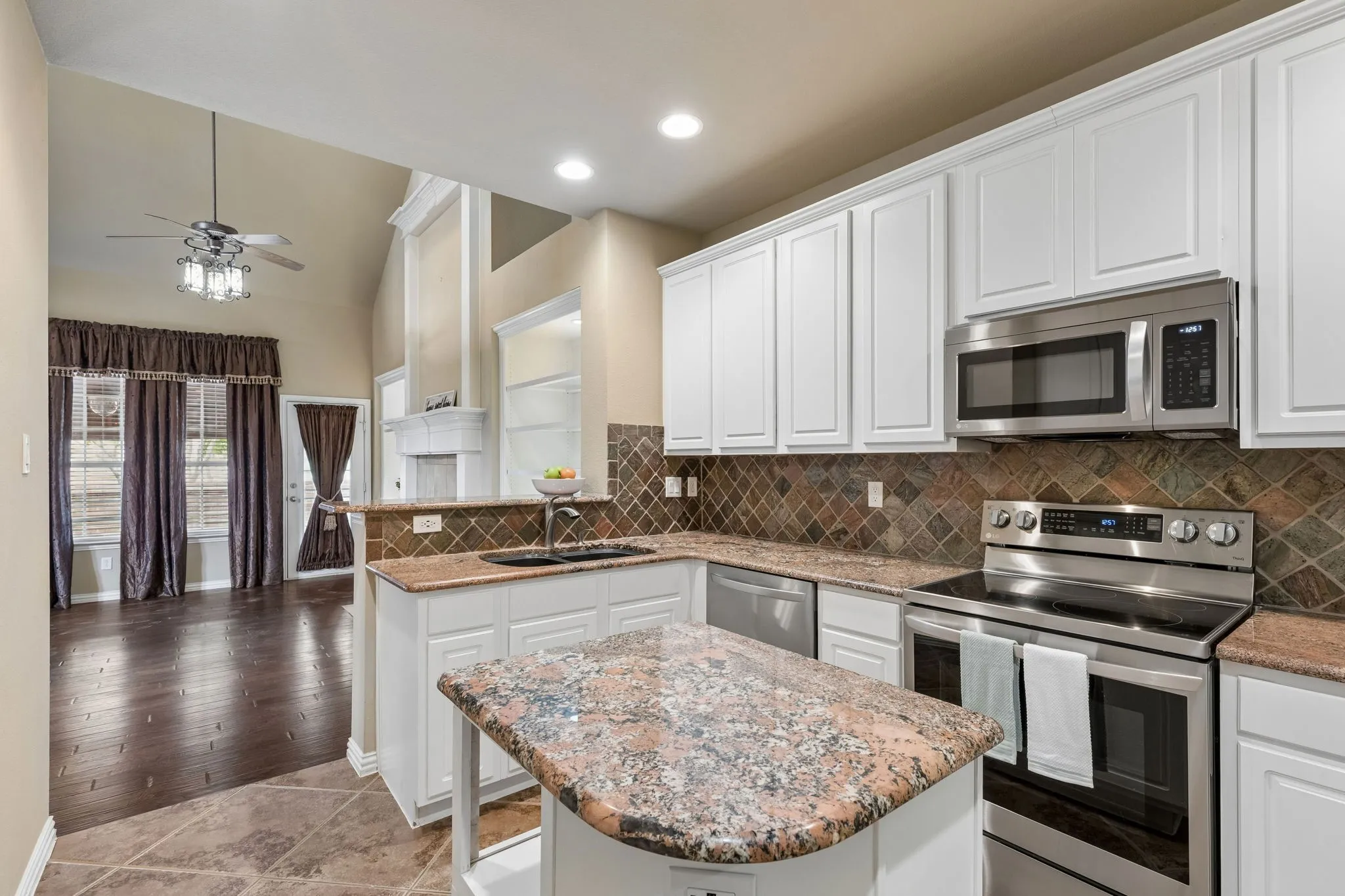 Kitchen features white cabinetry, stainless steel appliances, and granite countertops