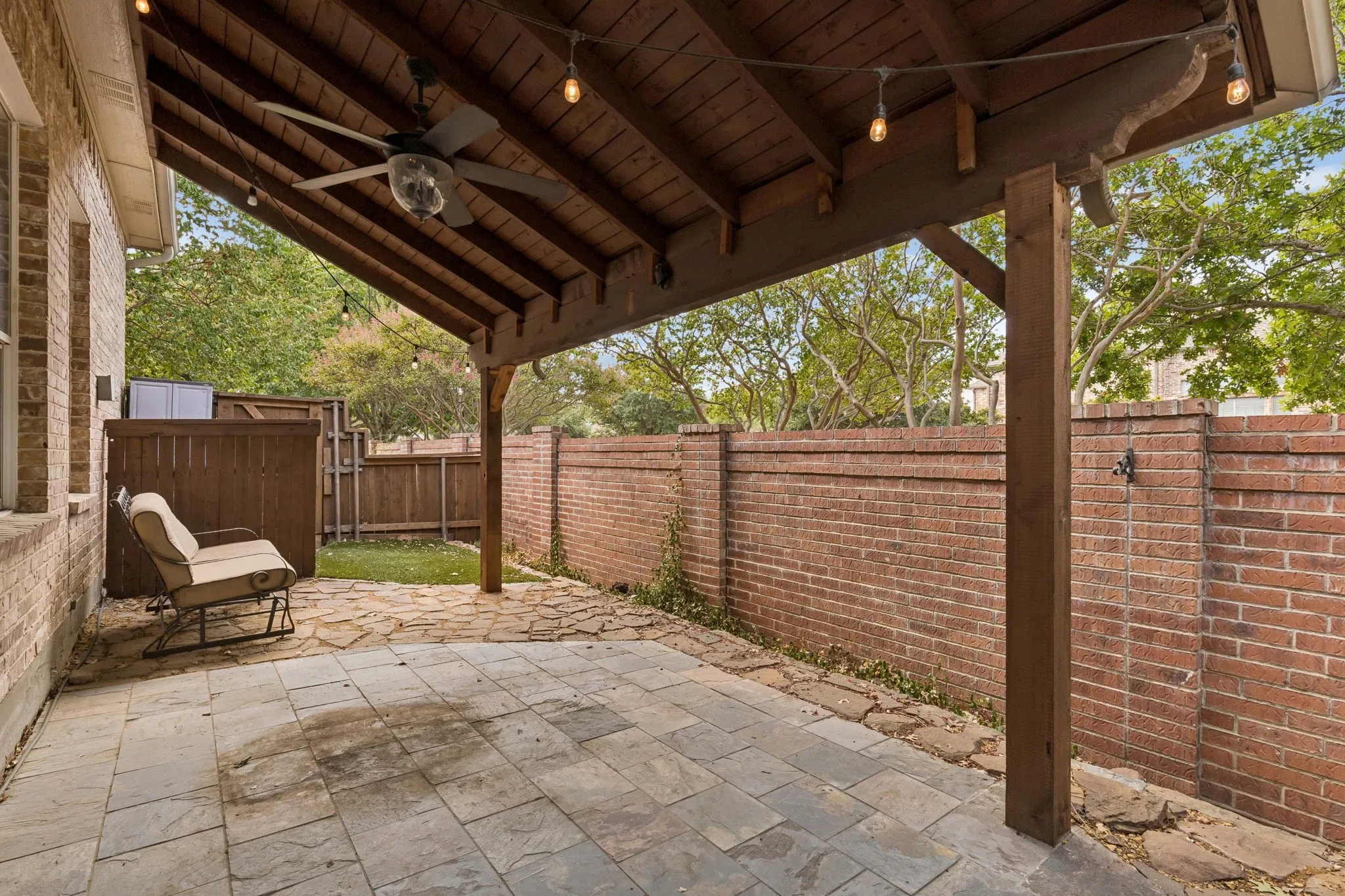 Covered patio featuring a wood ceiling with exposed beams, ceiling fan, and string lighting