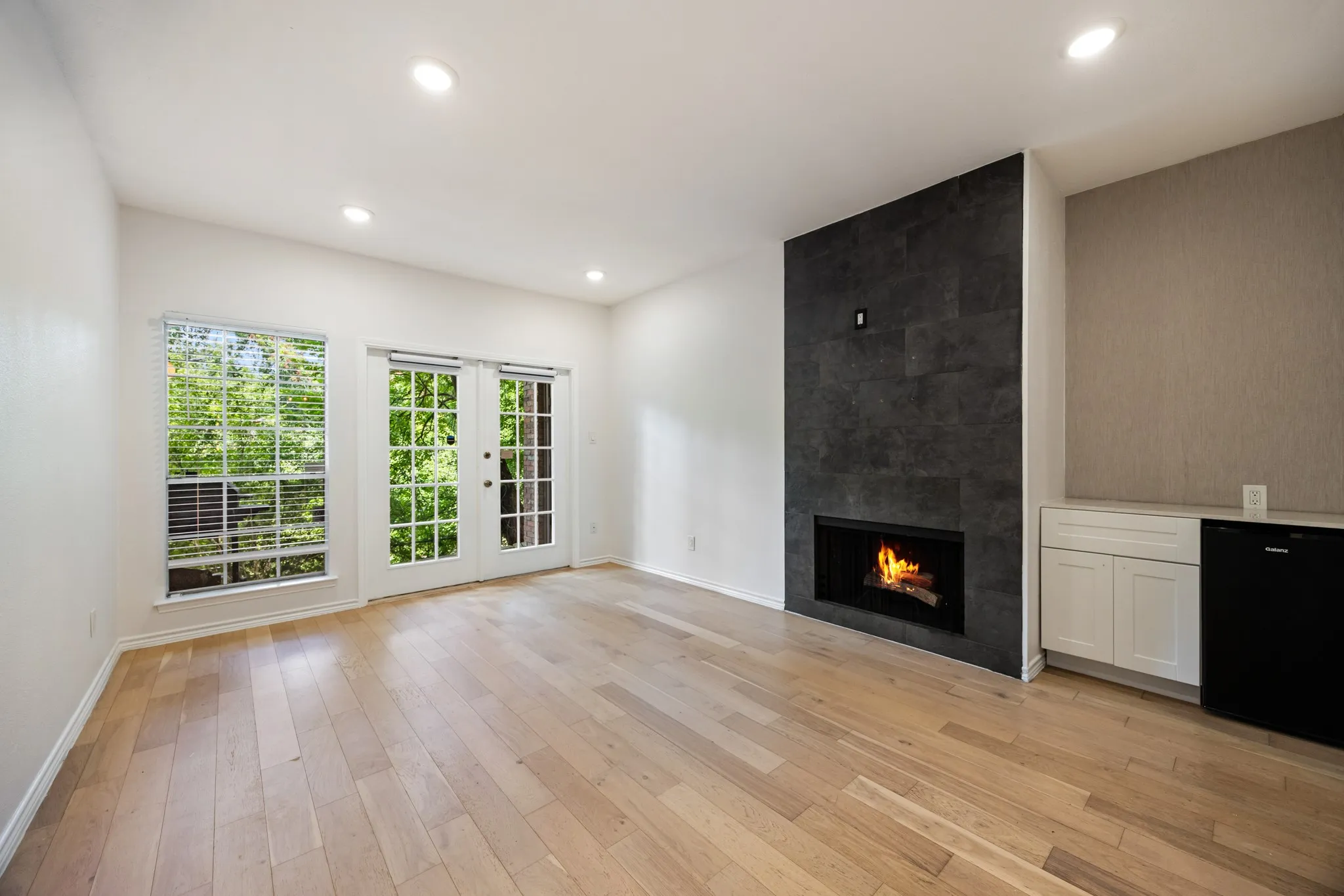 Light wood-finish flooring, recessed lighting, and a dark tile fireplace with an integrated firebox