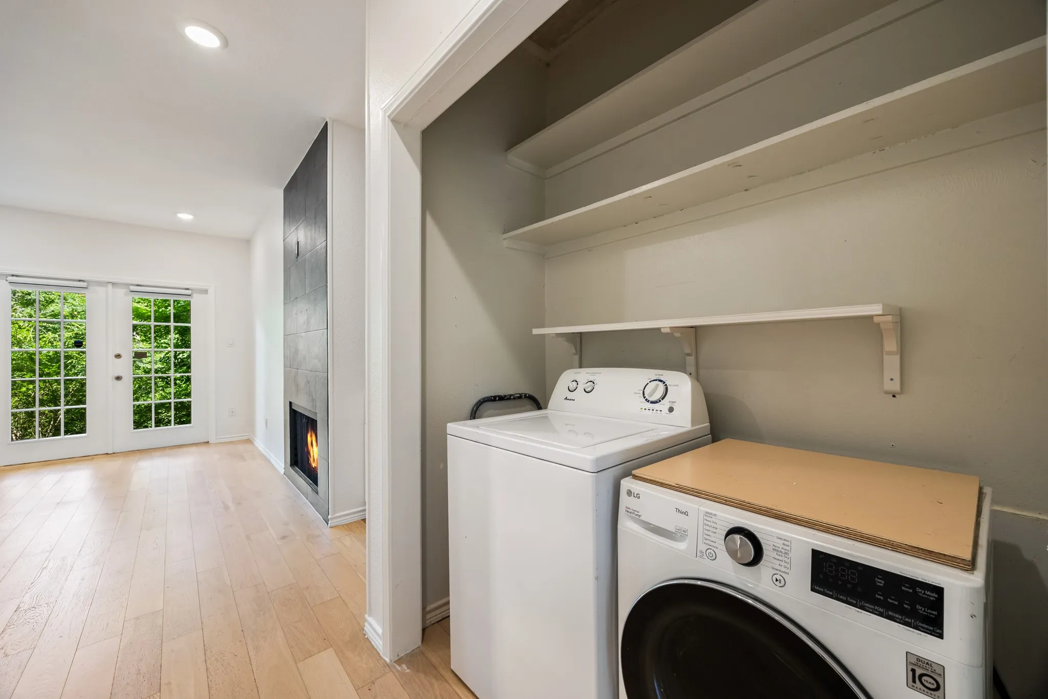 Recessed lighting, wood-finish flooring, two sets of double French doors, and a modern fireplace with dark tile surround