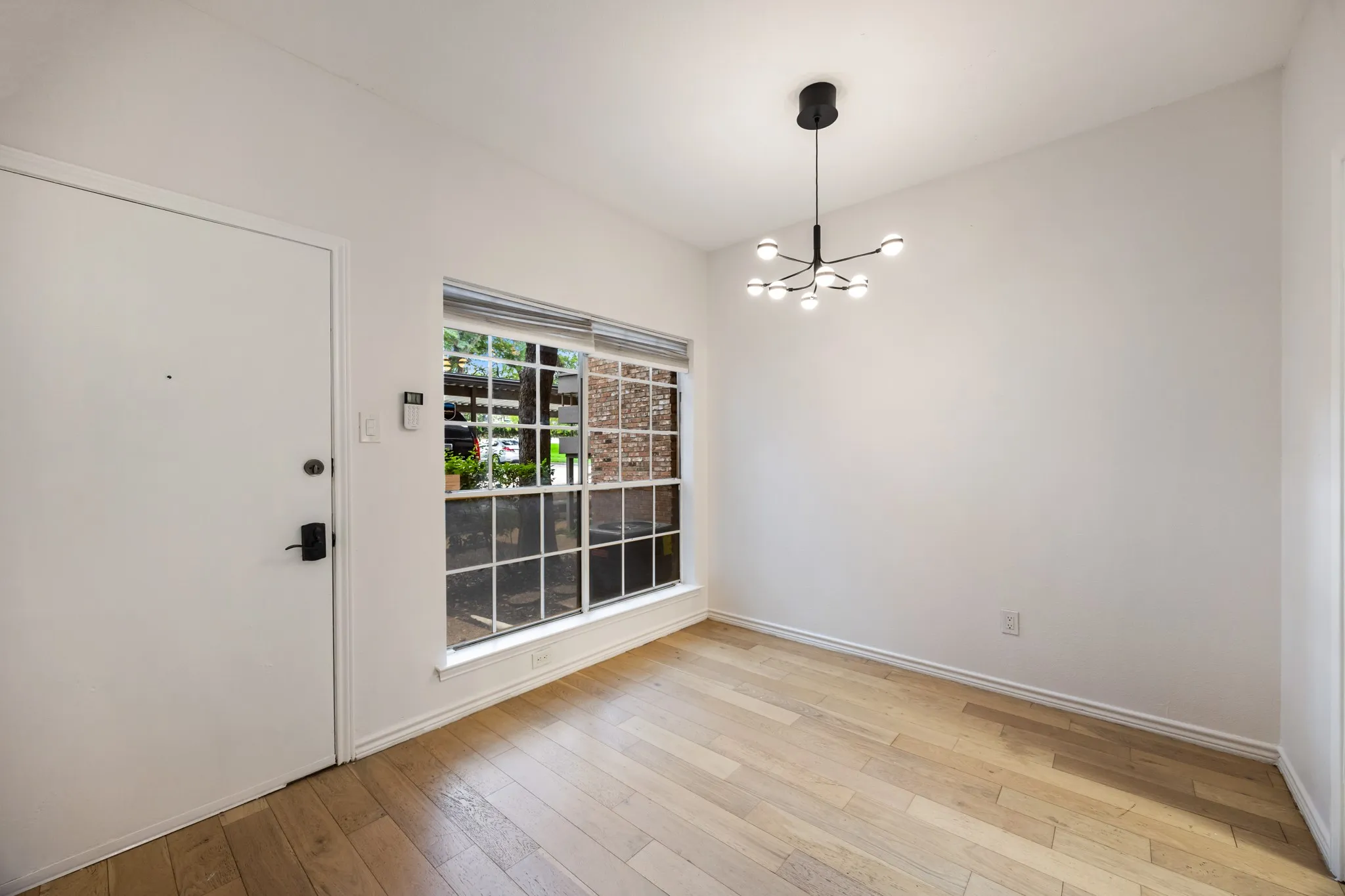 Wood-finish flooring, white walls, and a contemporary multi-bulb chandelier