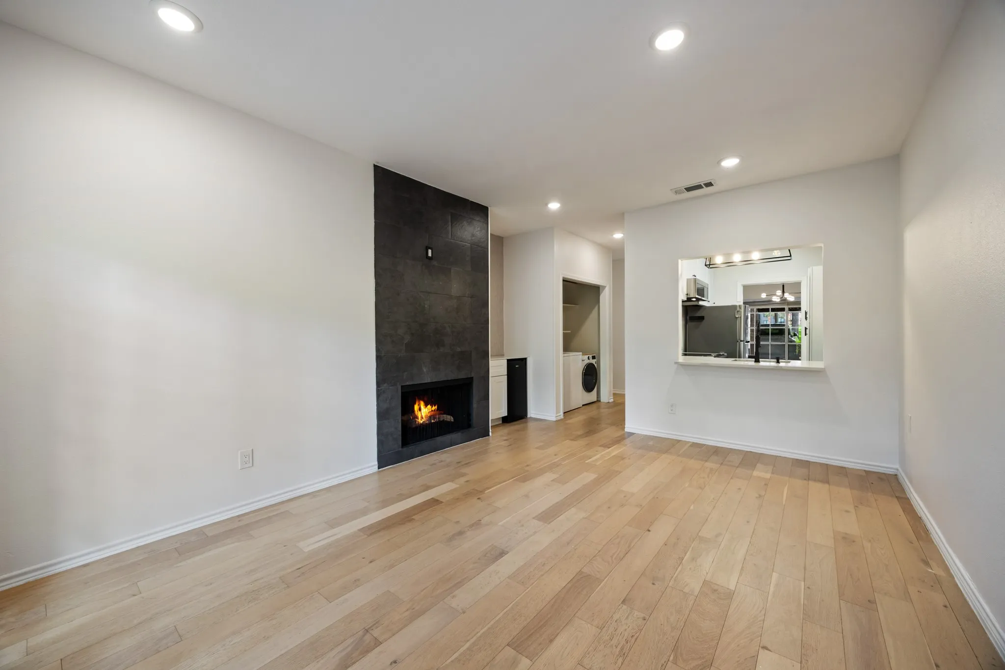 Wood-finish flooring, recessed lighting, and a modern fireplace with a dark stone-look surround