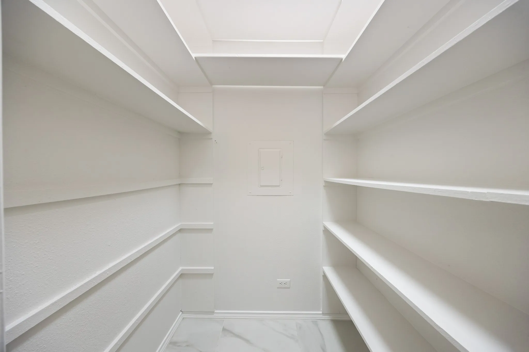 Recessed ceiling with integrated lighting, extensive built-in shelving, textured wall finish, and marble-look flooring