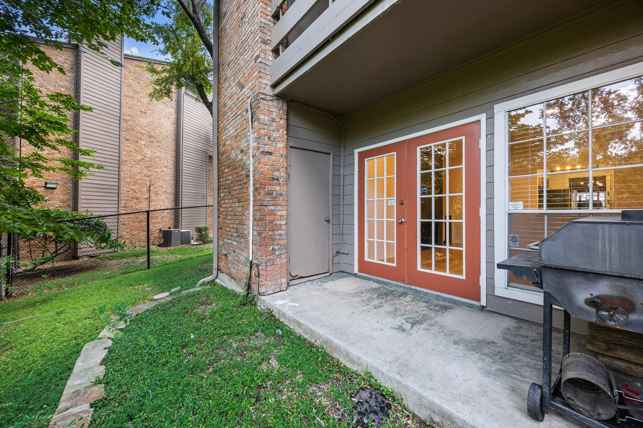 Red-framed French doors, large picture window, and a concrete patio space