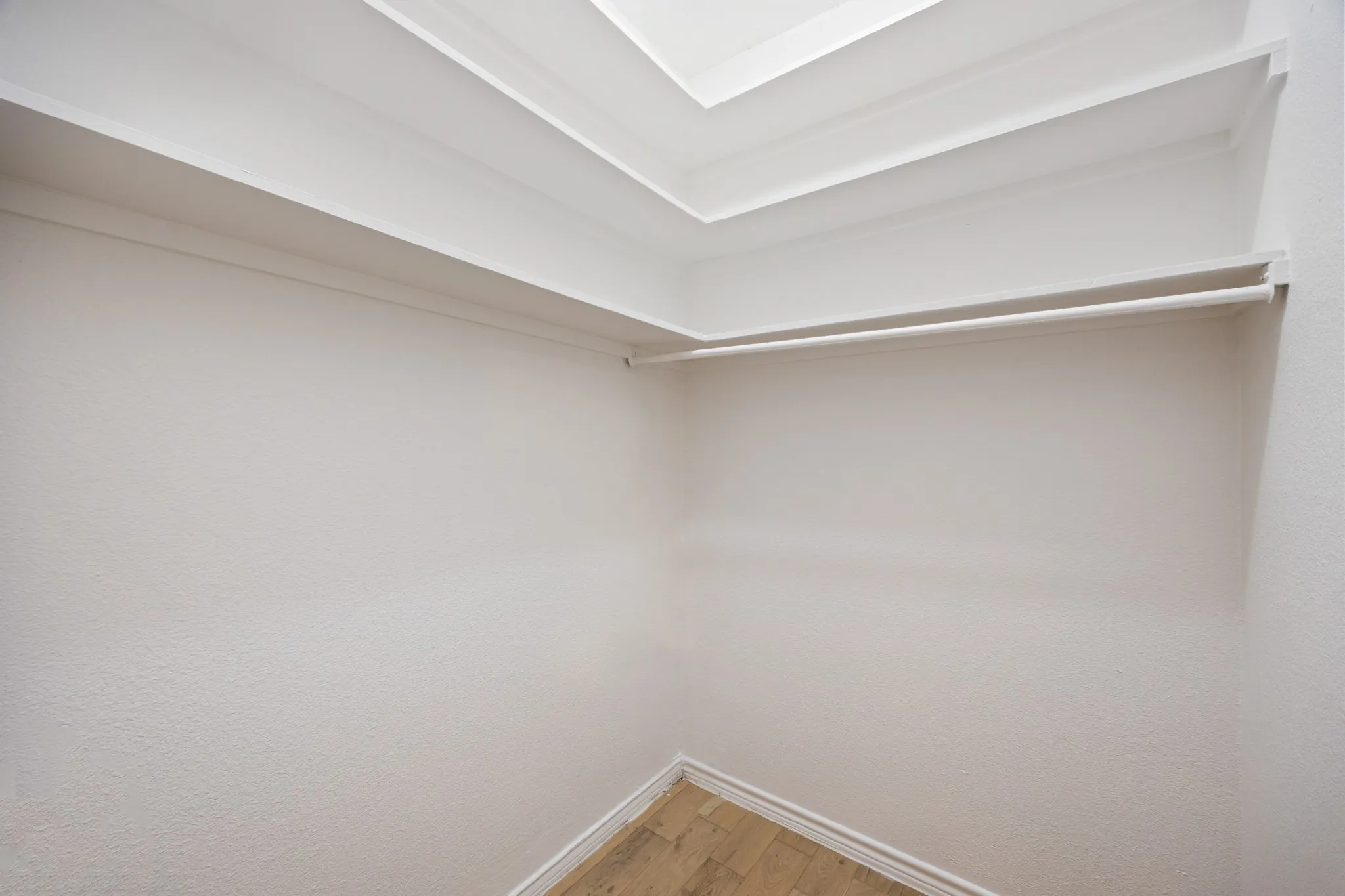 Recessed ceiling lighting, crown molding, wall-mounted shelving, and wood-finish flooring