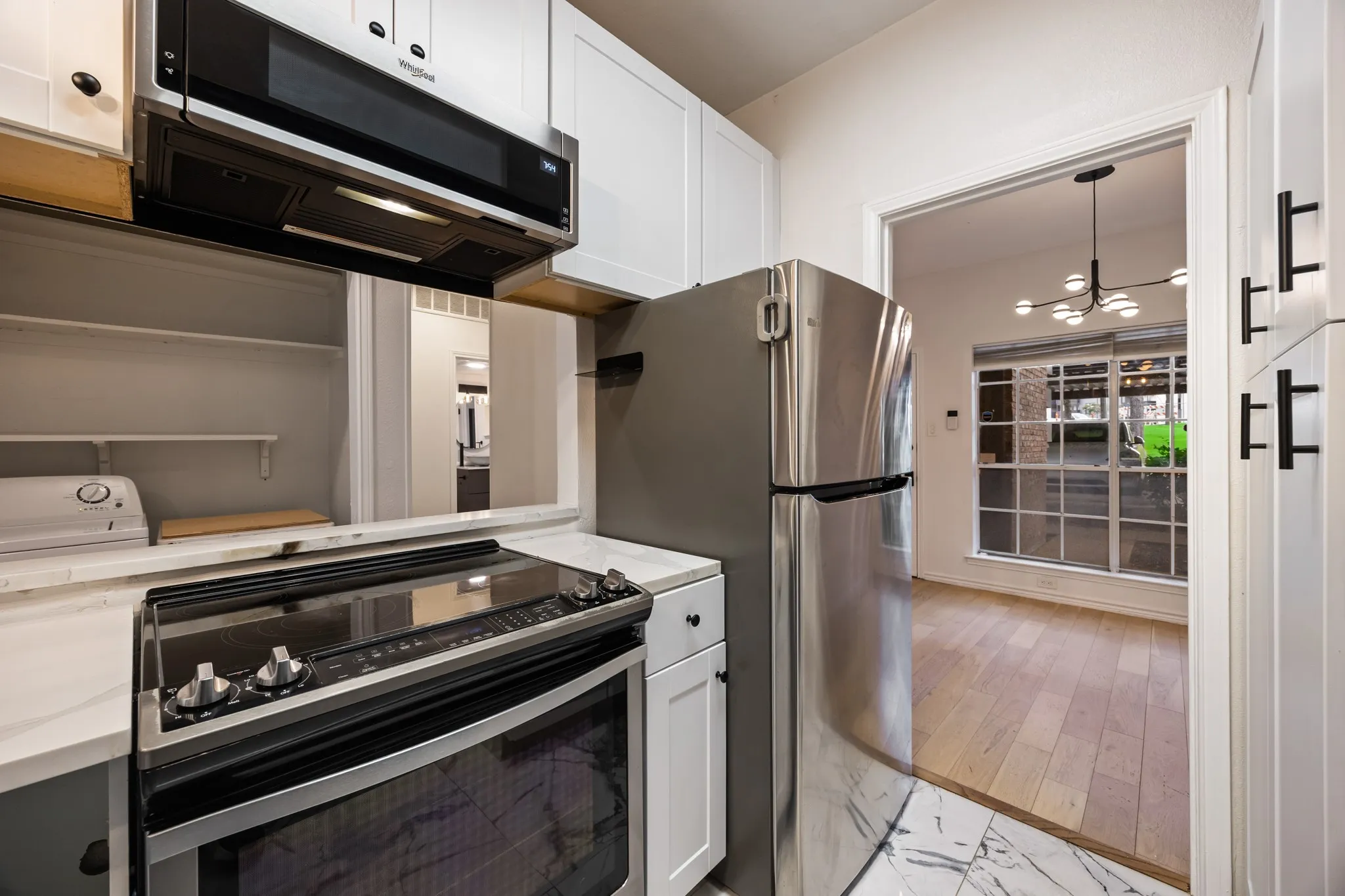 White cabinetry, stainless steel appliances, electric range, quartz countertops, and marble-finish tile flooring