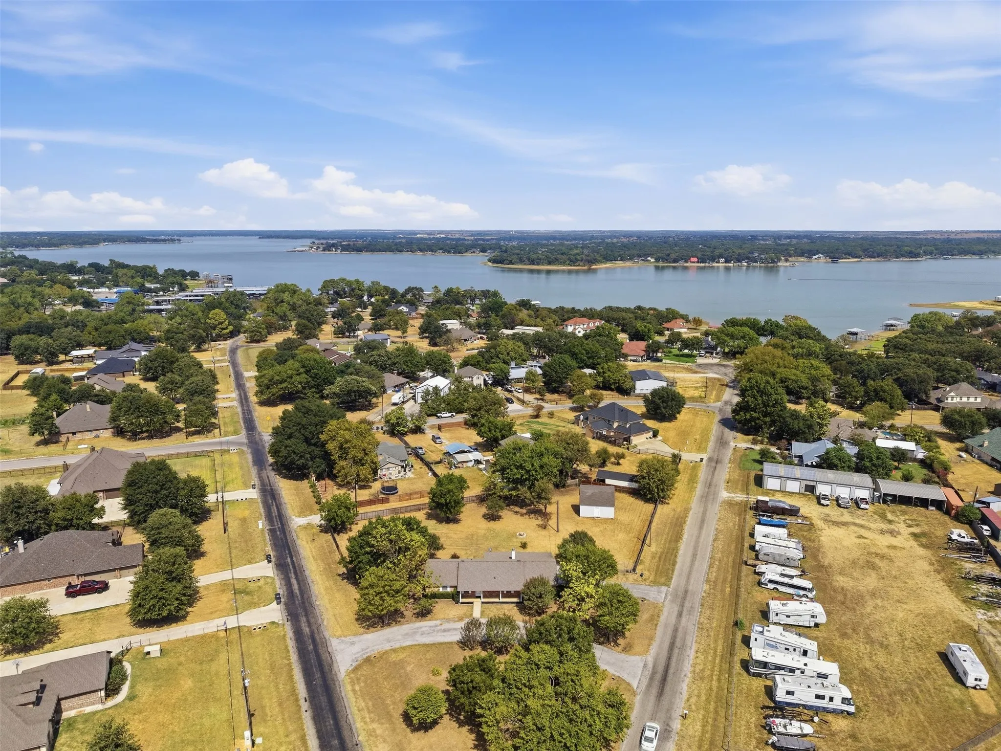 Aerial perspective of a developed residential area with established trees and a distant body of water