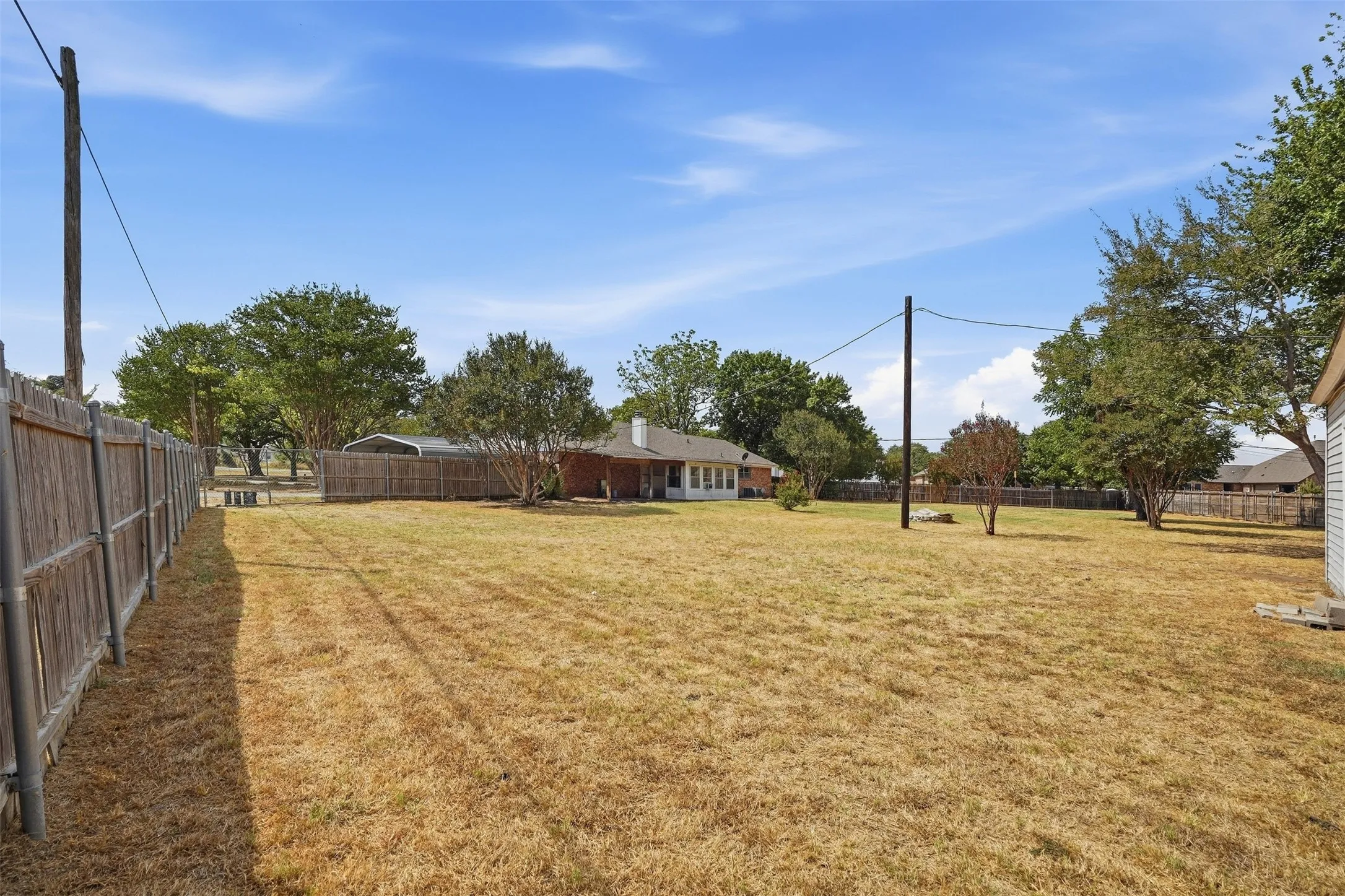 Expansive backyard featuring a wood privacy fence, mature trees, and a detached shed