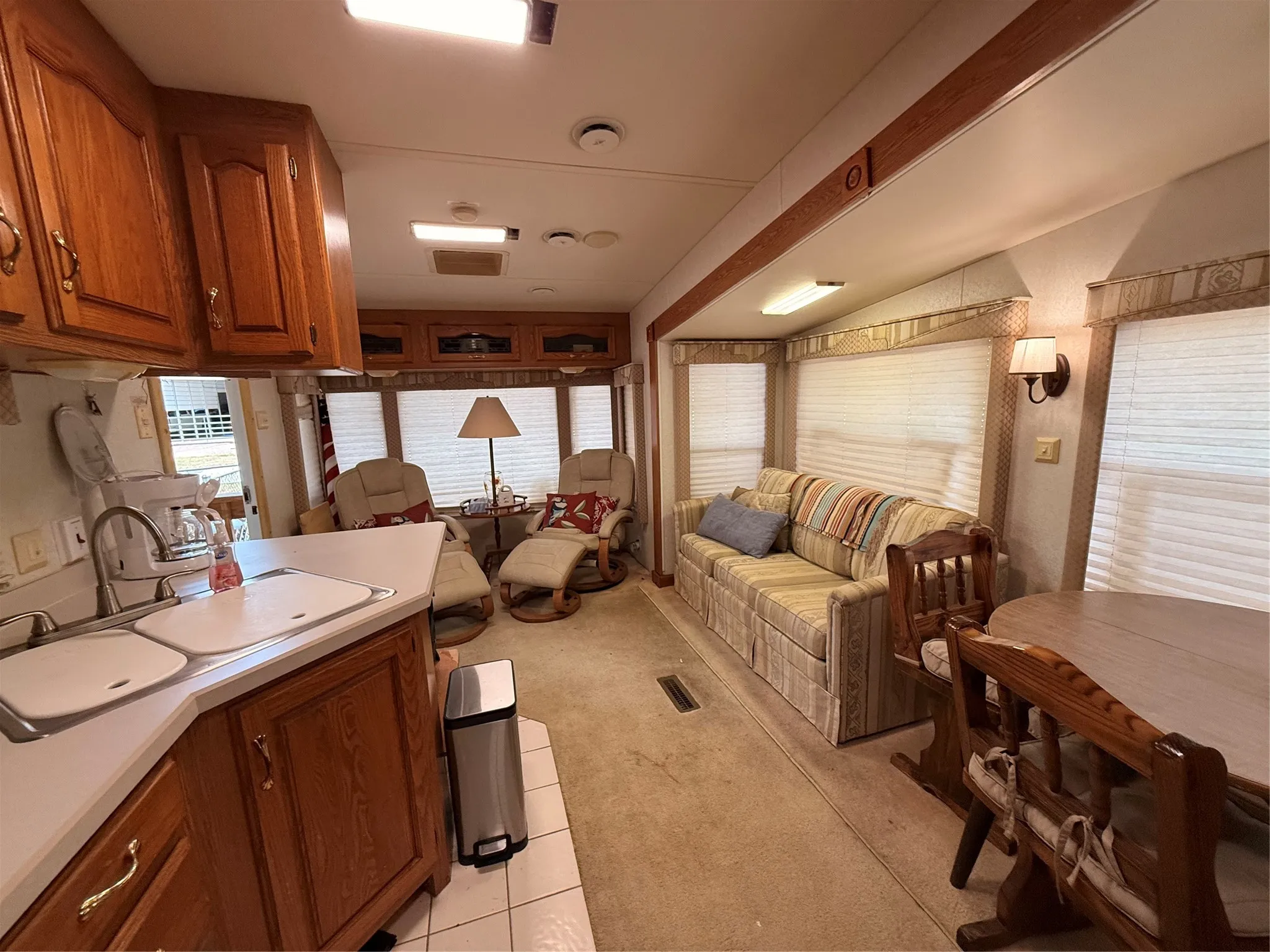 Wood-finish cabinetry, built-in sink, white countertop, and wall-mounted lighting fixtures