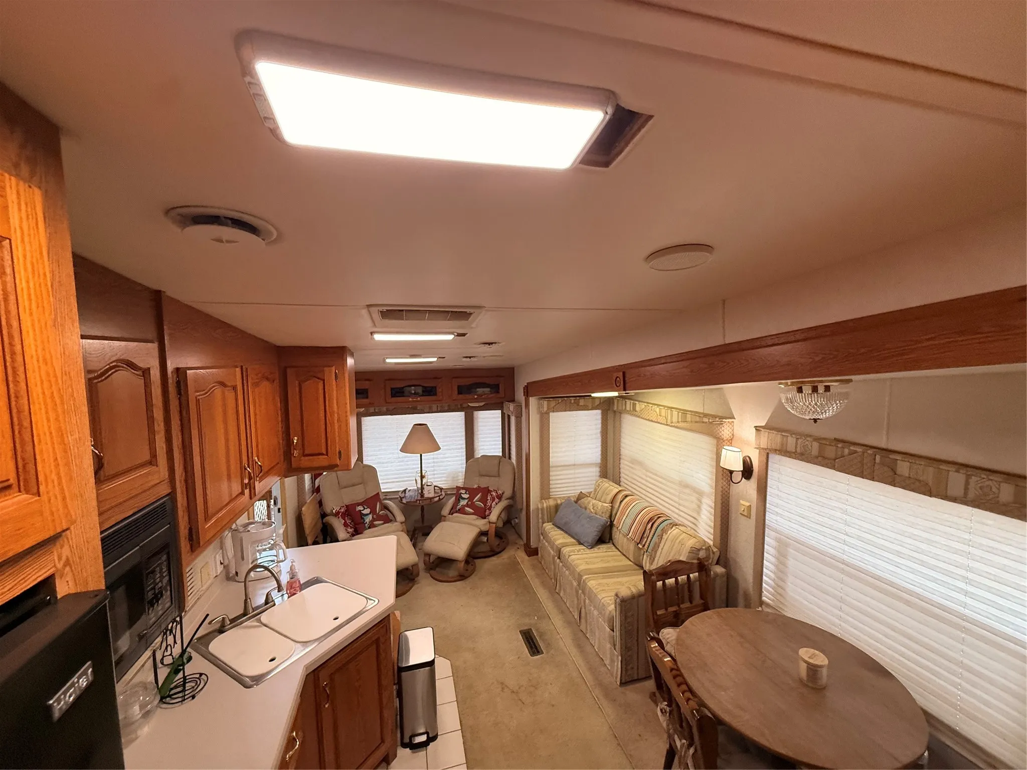 Wood-finish cabinetry, built-in microwave, integrated double sink, recessed lighting, and window treatments throughout