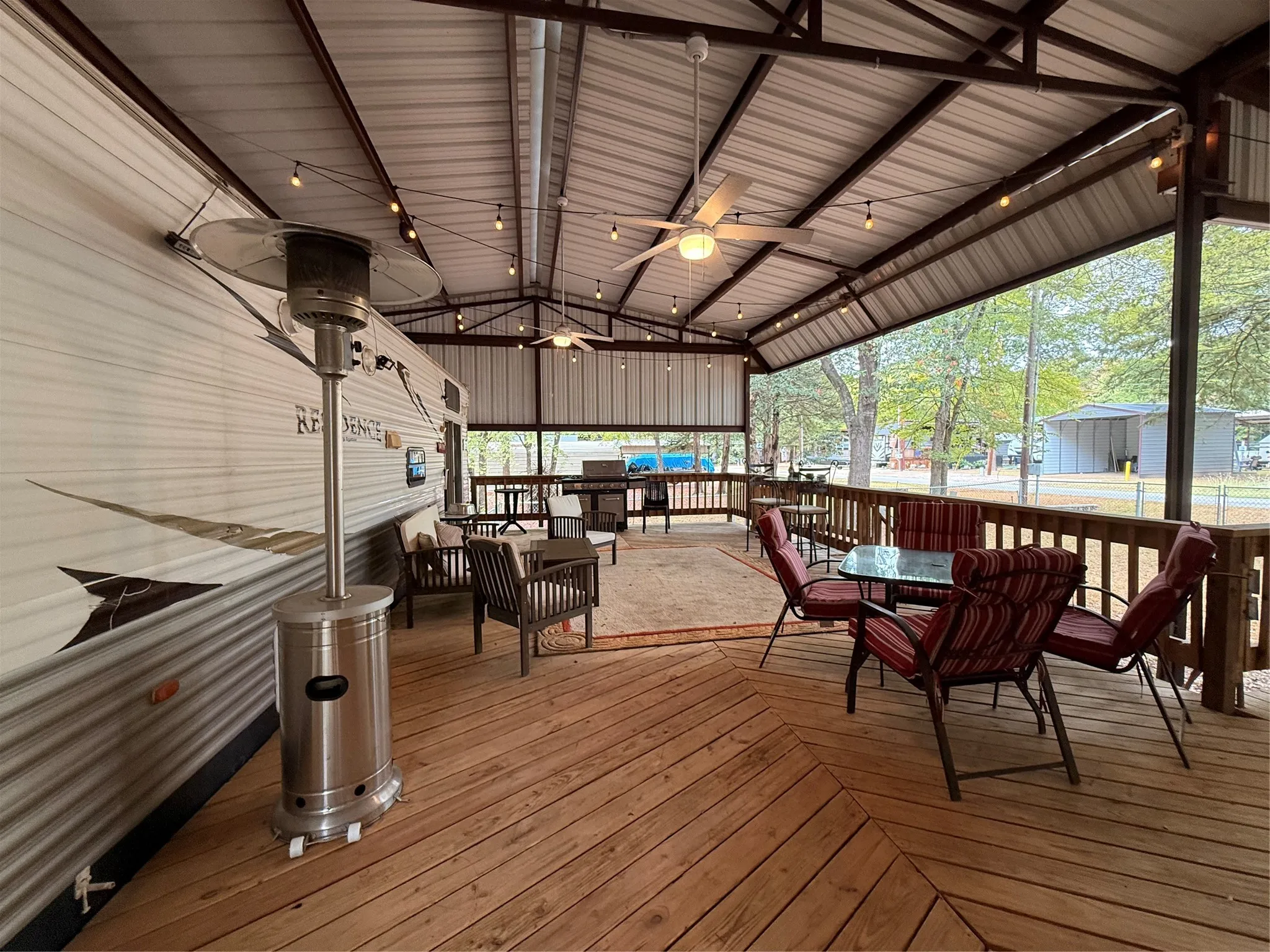 Expansive covered outdoor deck featuring wood flooring, exposed beam ceiling, and string lighting