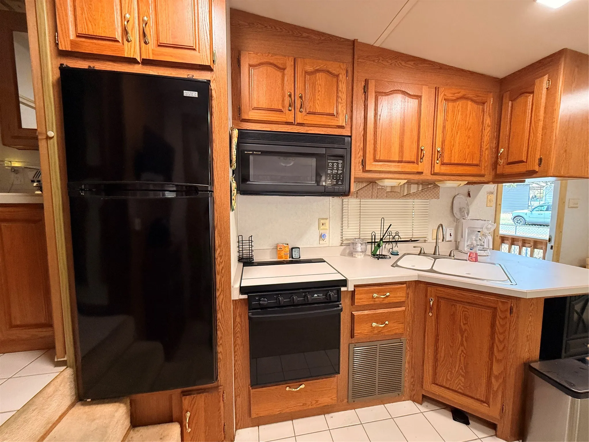 Kitchen featuring wood-finish cabinetry, black refrigerator, built-in microwave, and a double basin sink