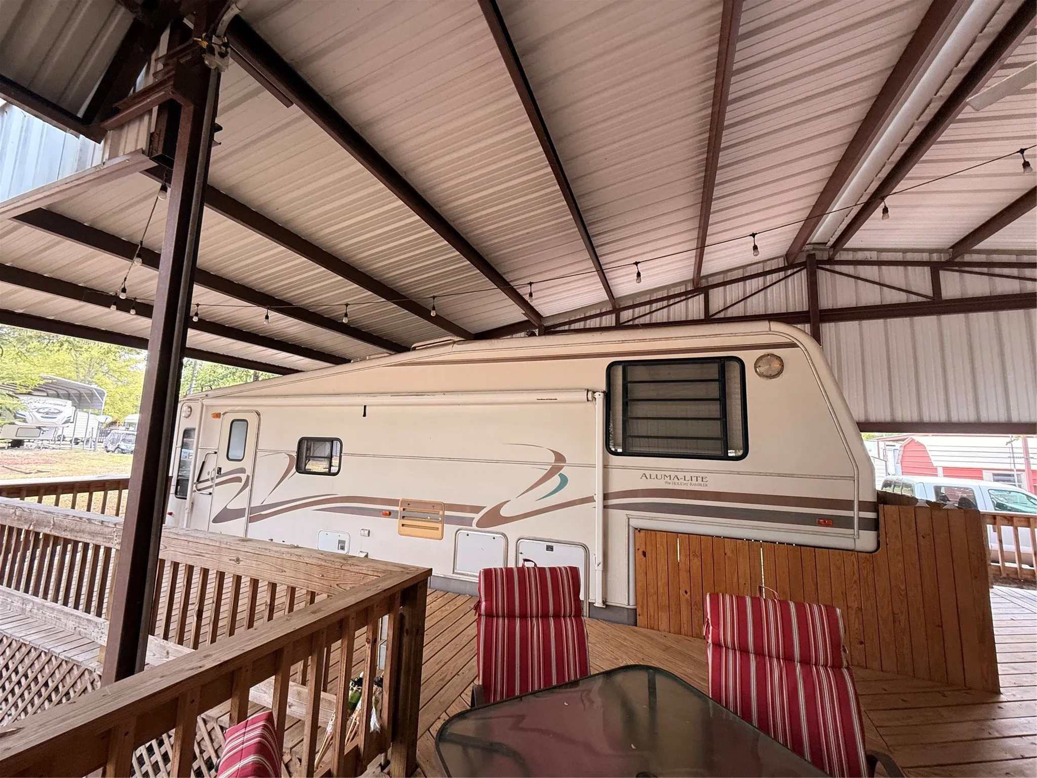 Expansive covered outdoor living area featuring a wood-finish deck and a metal roof structure
