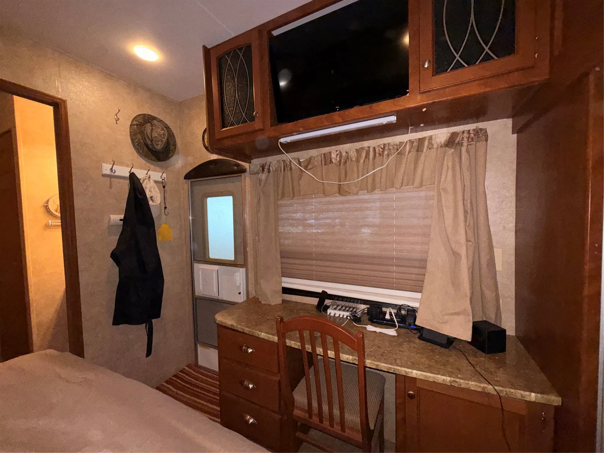 Built-in desk with a stone-finish countertop, wood-finish cabinetry, and overhead storage