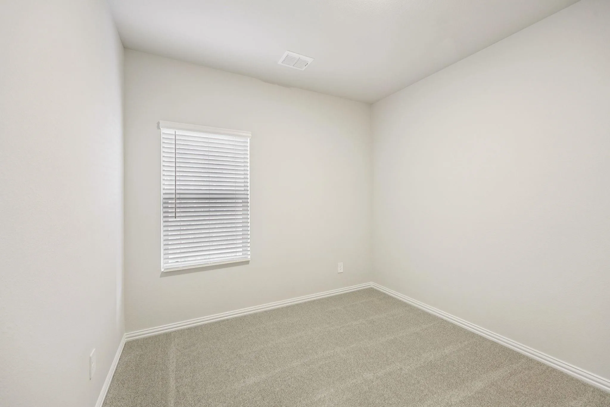Neutral wall finishes, light-toned carpet, and a window with horizontal blinds