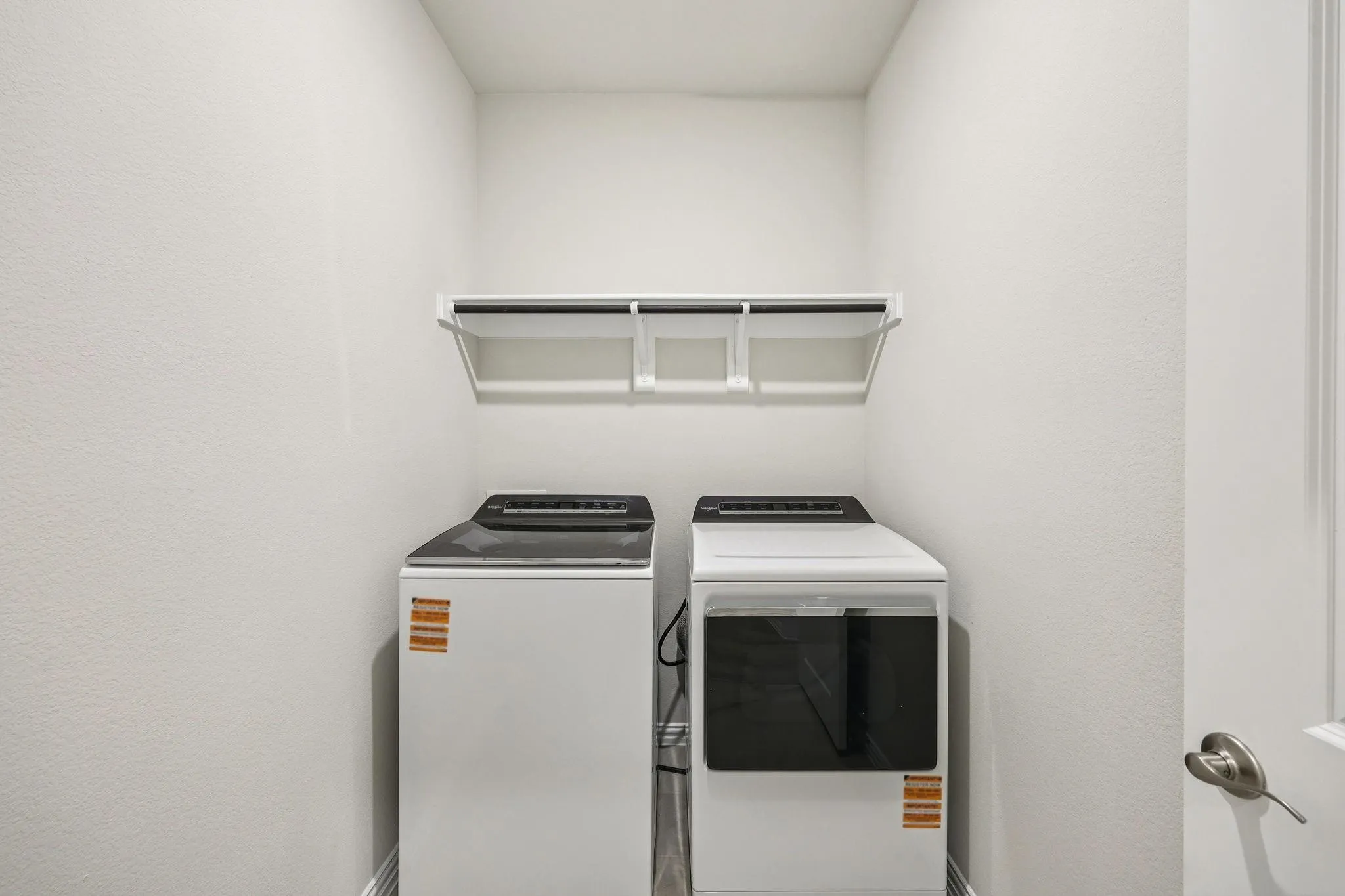 Dedicated laundry space featuring a white shelf and hanging rod