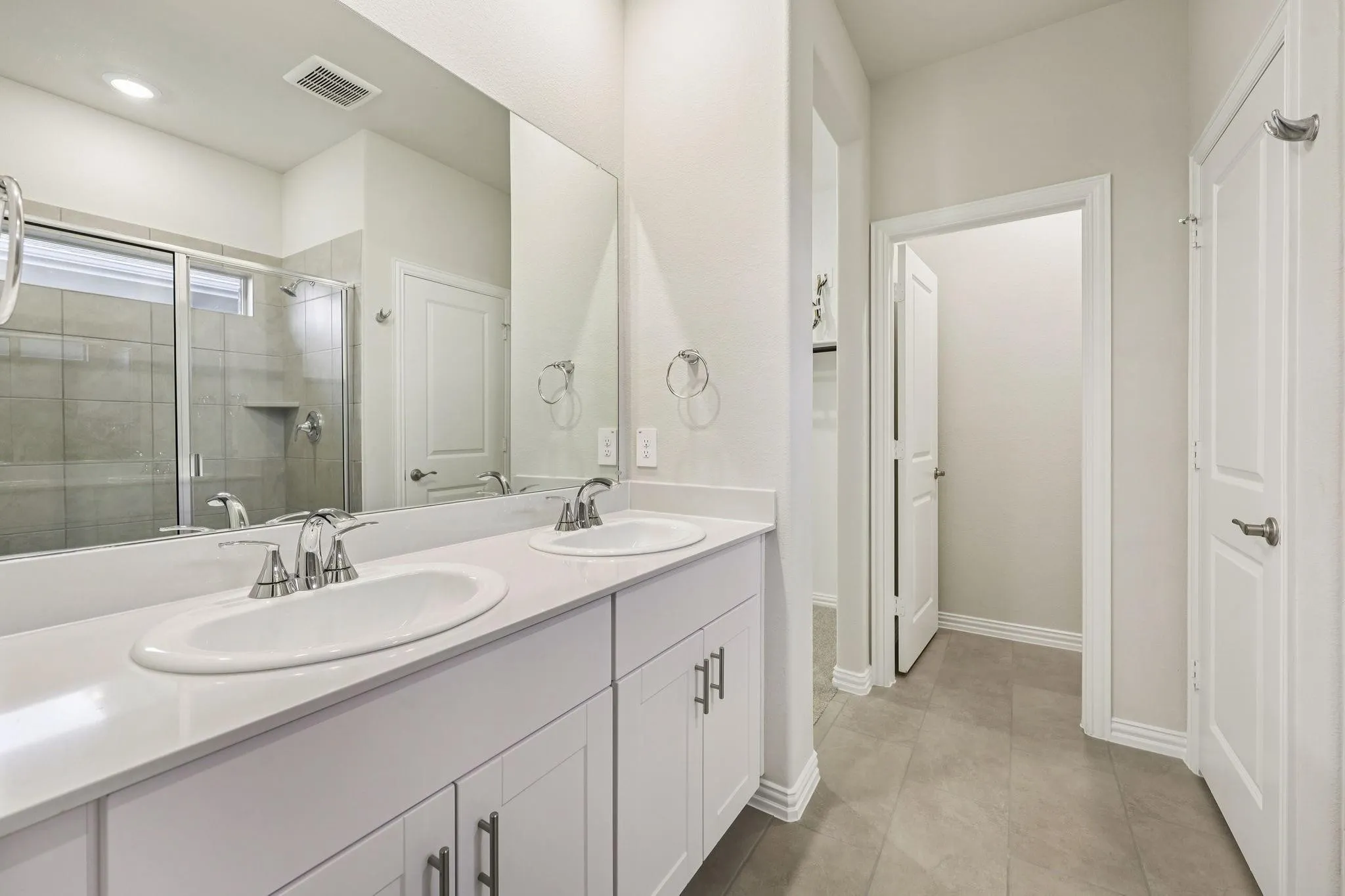 Dual vanity with undermount sinks, chrome fixtures, and white cabinetry