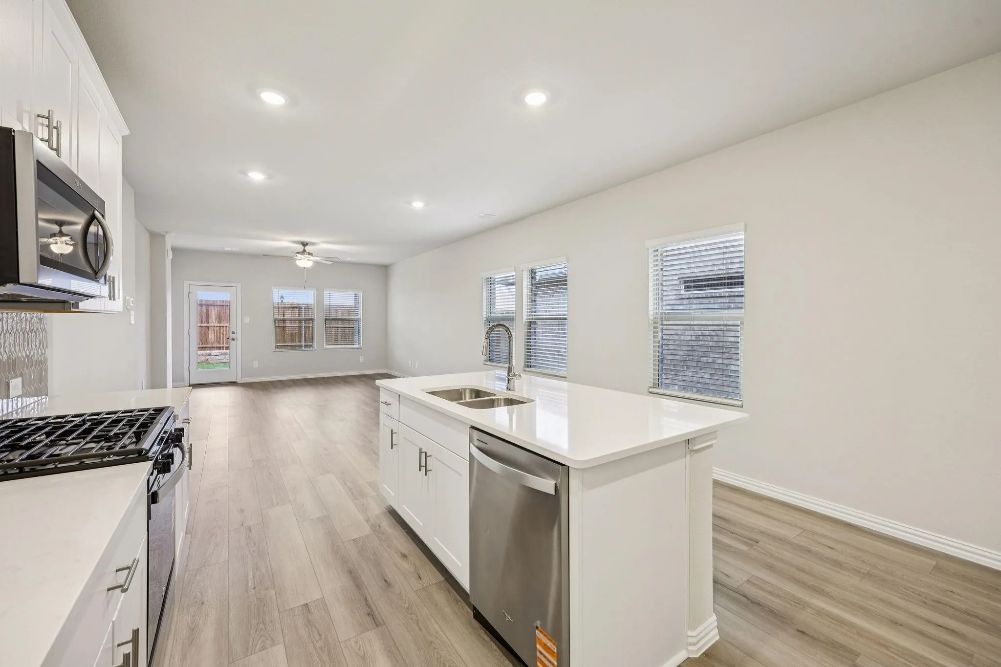 Kitchen island with a stainless steel sink, white cabinetry, and a dishwasher