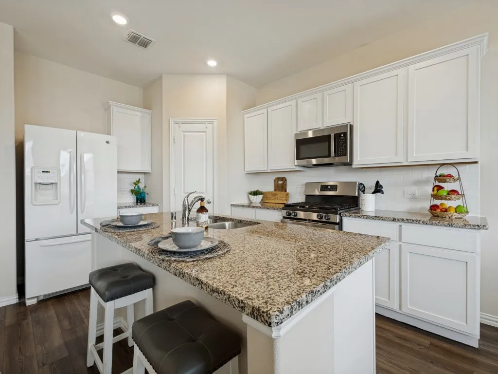 Beautiful granite countertops and a gas range with microwave above.