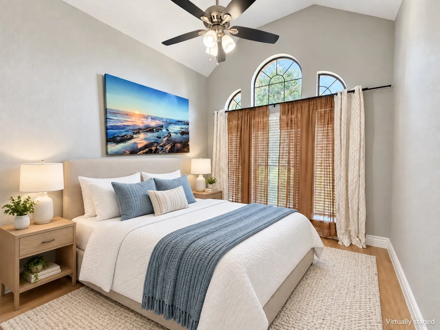 Vaulted ceiling with a ceiling fan, arched windows, wood-finish flooring, and a neutral color palette