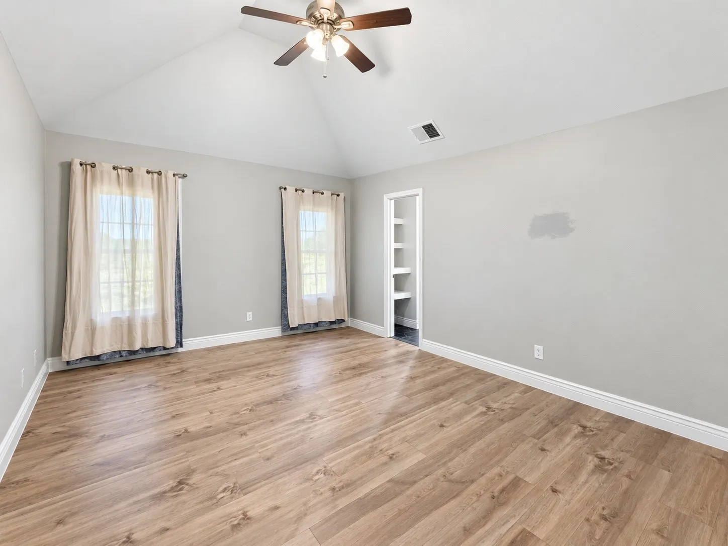 Vaulted ceiling with a ceiling fan, wood-finish flooring, and built-in shelving