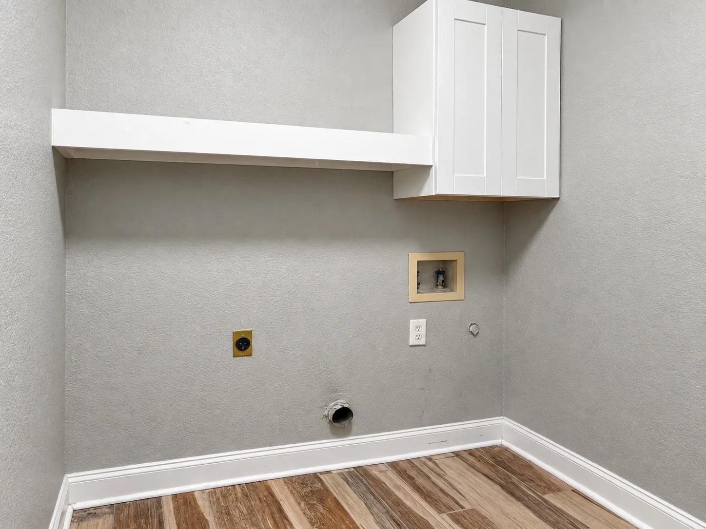 White shaker-style cabinetry, wood-finish flooring, white wall shelving, and white baseboard trim