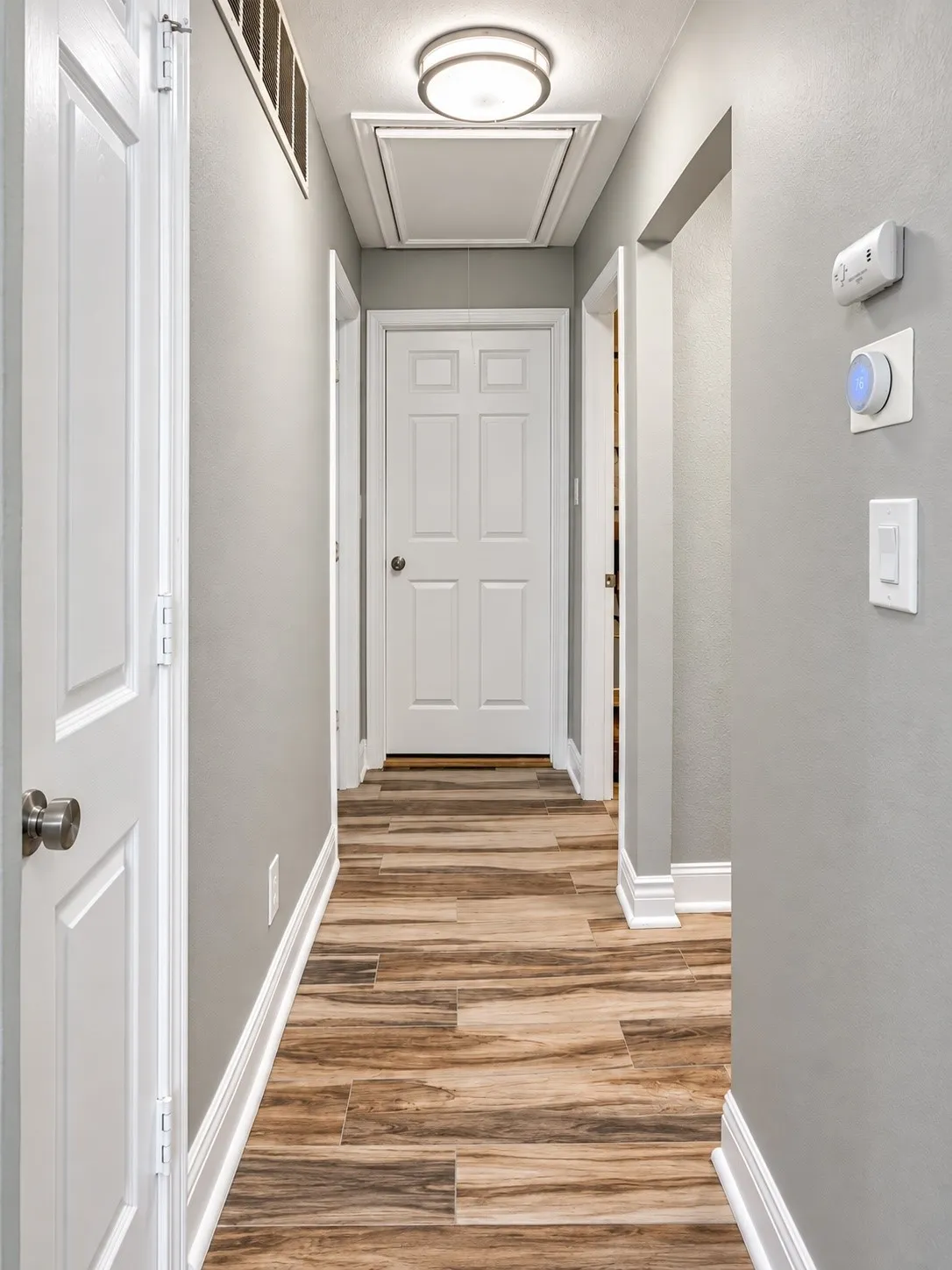 Wood-finish flooring, crisp white trim, recessed ceiling light, and interior doors with brushed nickel hardware