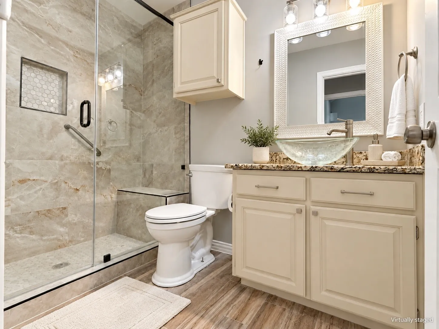 Glass-enclosed shower with a built-in bench, hexagonal tile niche, and natural stone-look tile