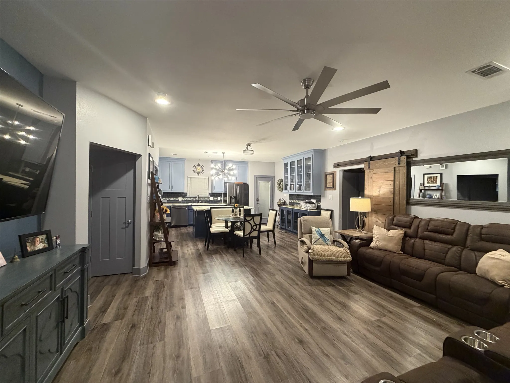Open-concept living space featuring wood-finish flooring, a contemporary ceiling fan, and a barn door