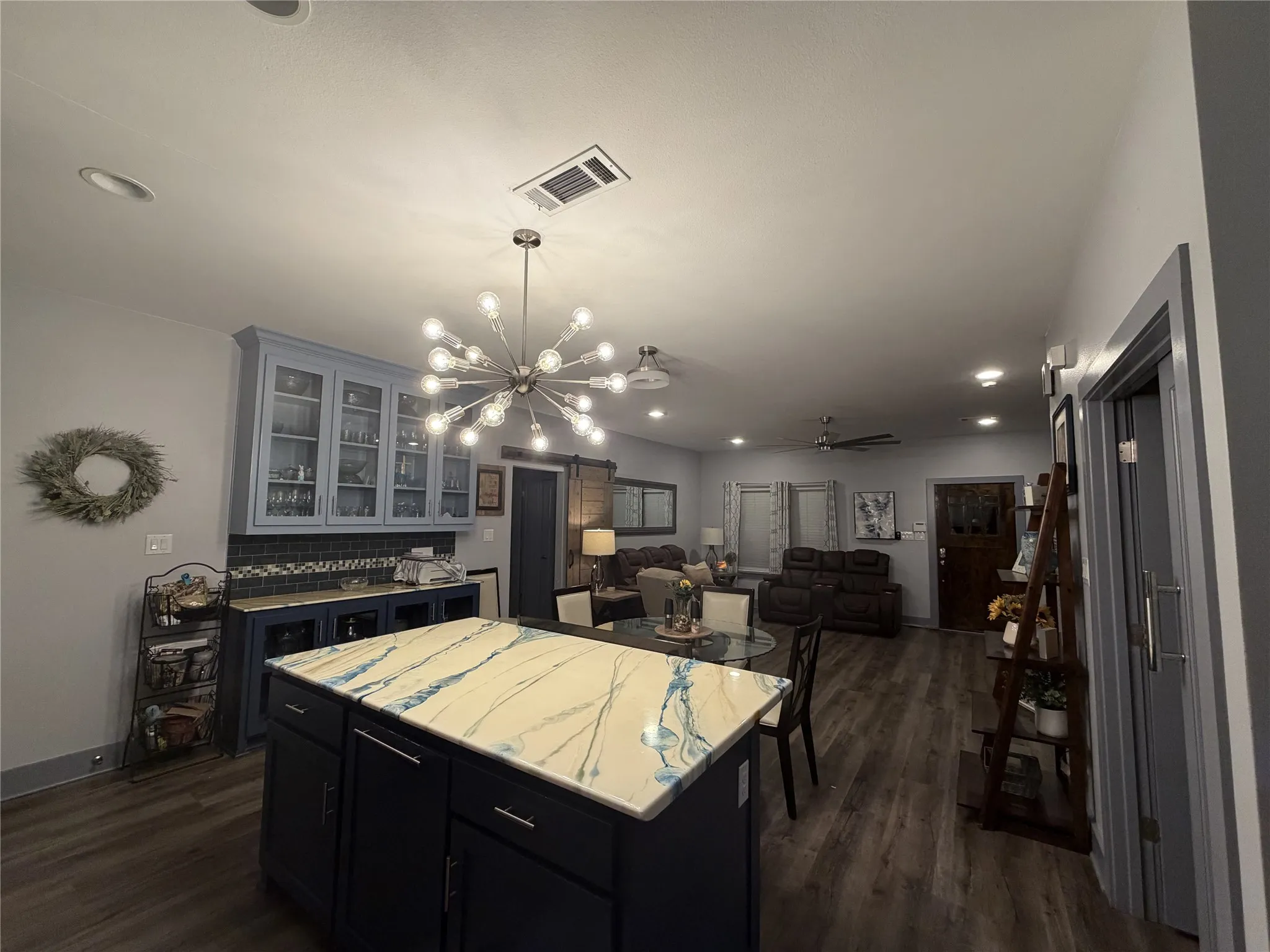 Open-concept living area with wood-finish flooring, recessed lighting, and a contemporary sputnik chandelier