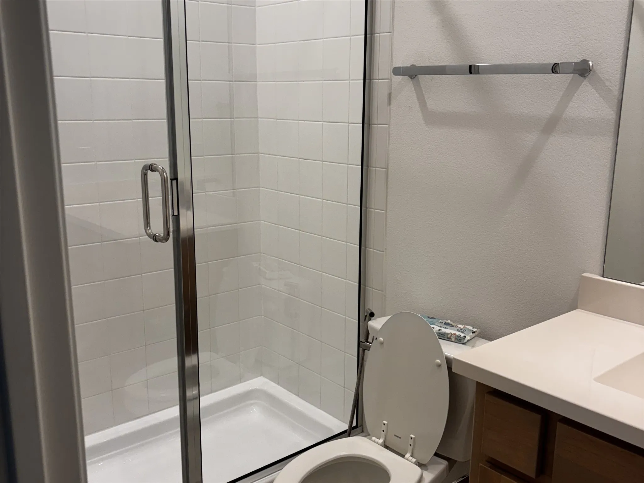 Glass-enclosed shower with white subway tile surround, white shower pan, and chrome hardware