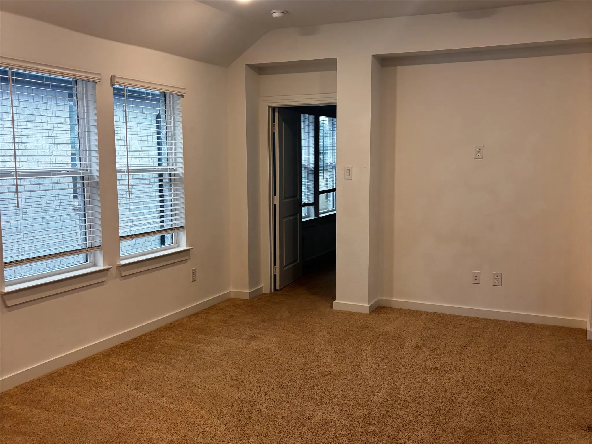 Carpeted room featuring two windows with white blinds, recessed lighting, and a vaulted ceiling detail