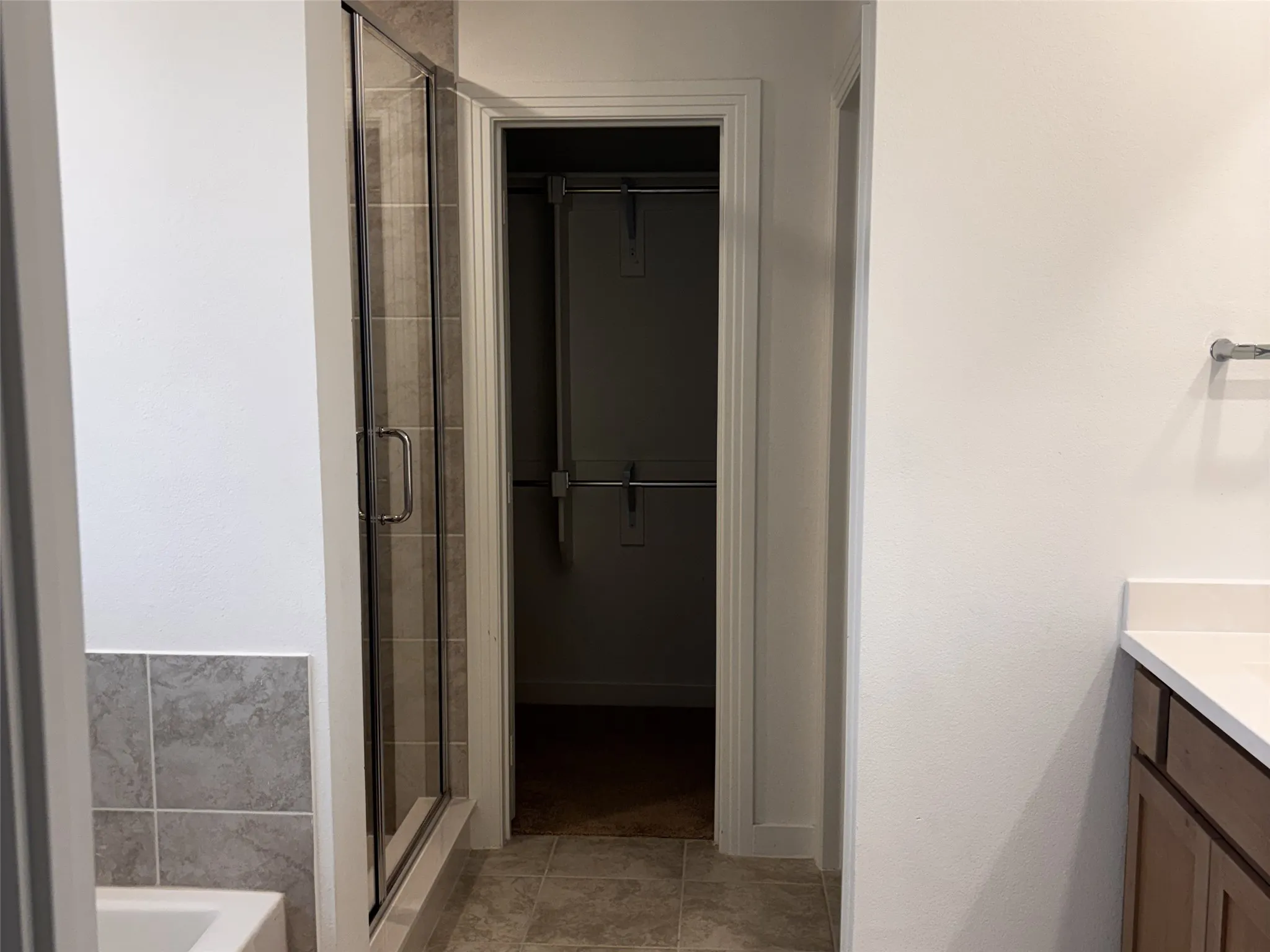 Glass-enclosed shower with tiled surround, separate tub, and built-in closet