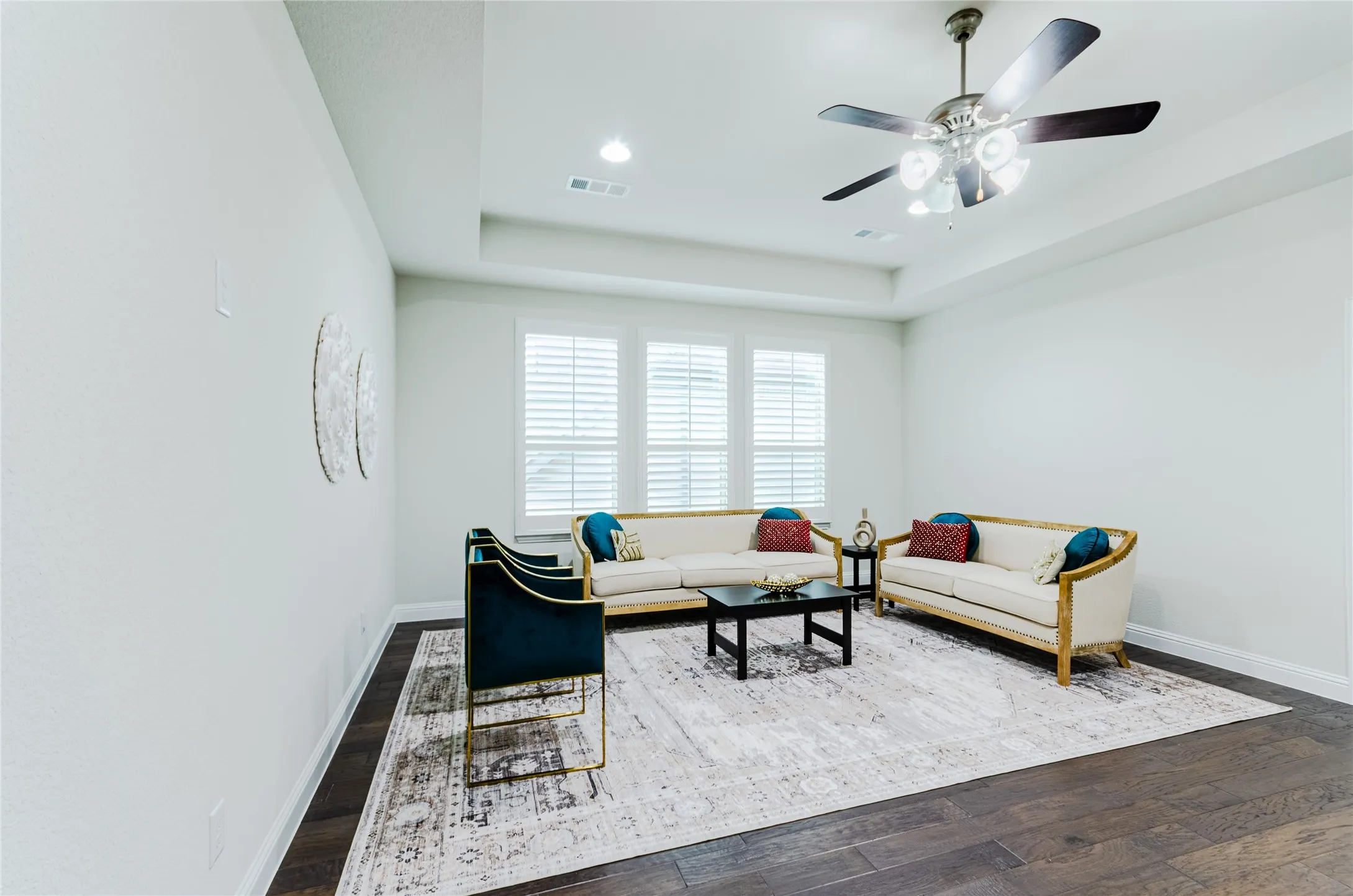 Spacious room featuring dark wood-finish flooring, white baseboards, and a tray ceiling with recessed lighting