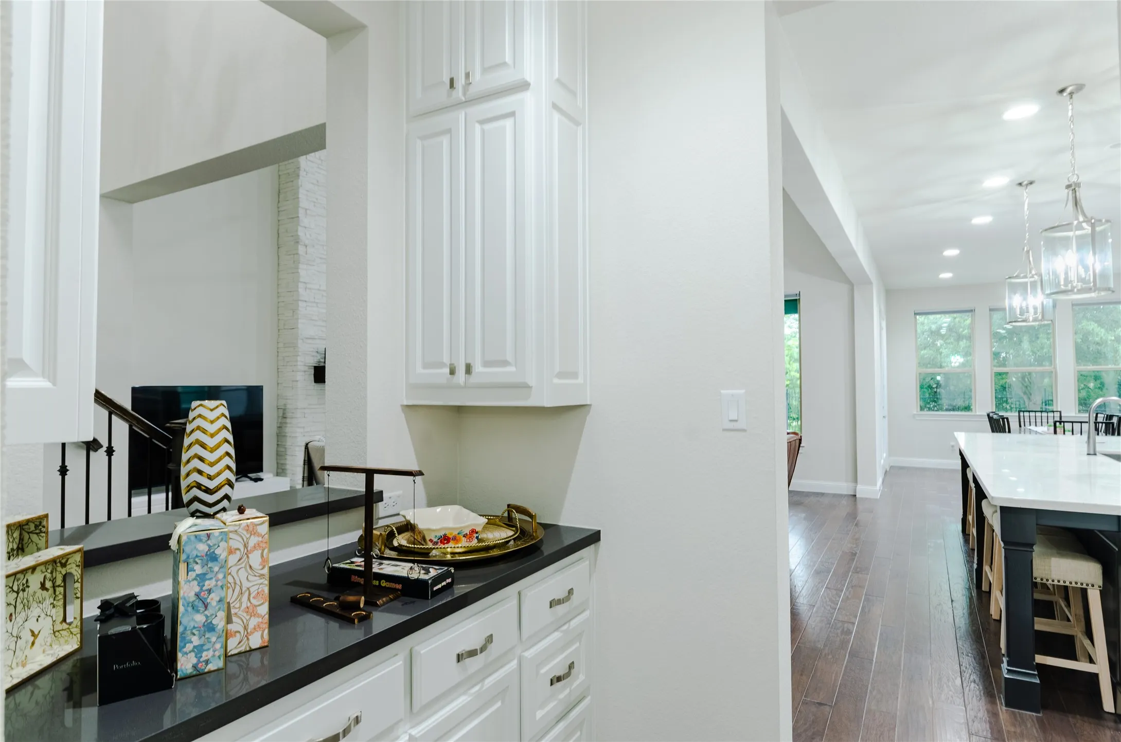 White cabinetry with a dark countertop and integrated storage, featuring a kitchen island with a white countertop, bar seating, and pendant lighting