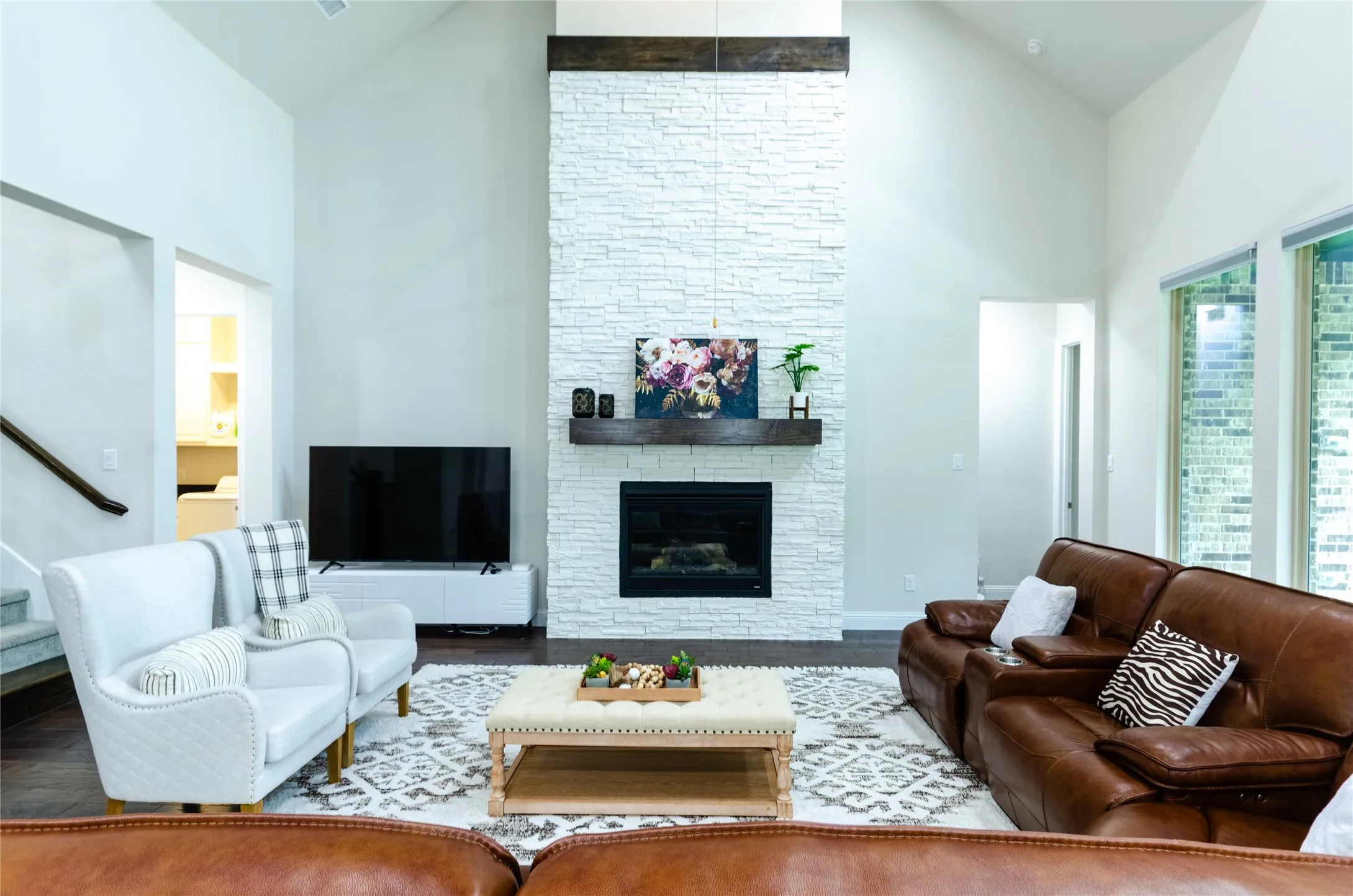 Vaulted living space featuring a floor-to-ceiling stacked stone fireplace with a wood mantle