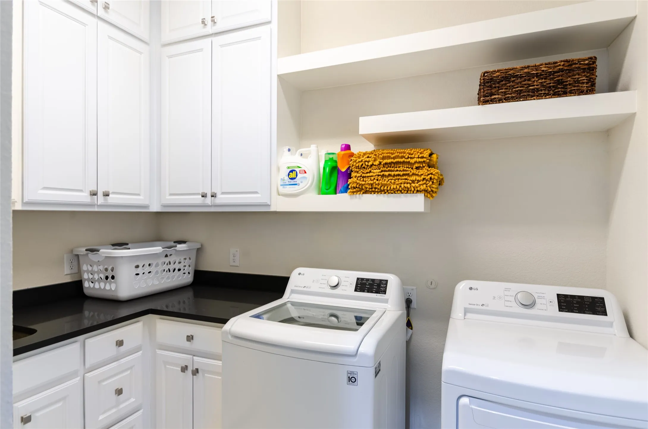 Laundry room featuring white cabinetry, dark countertops, and open shelving